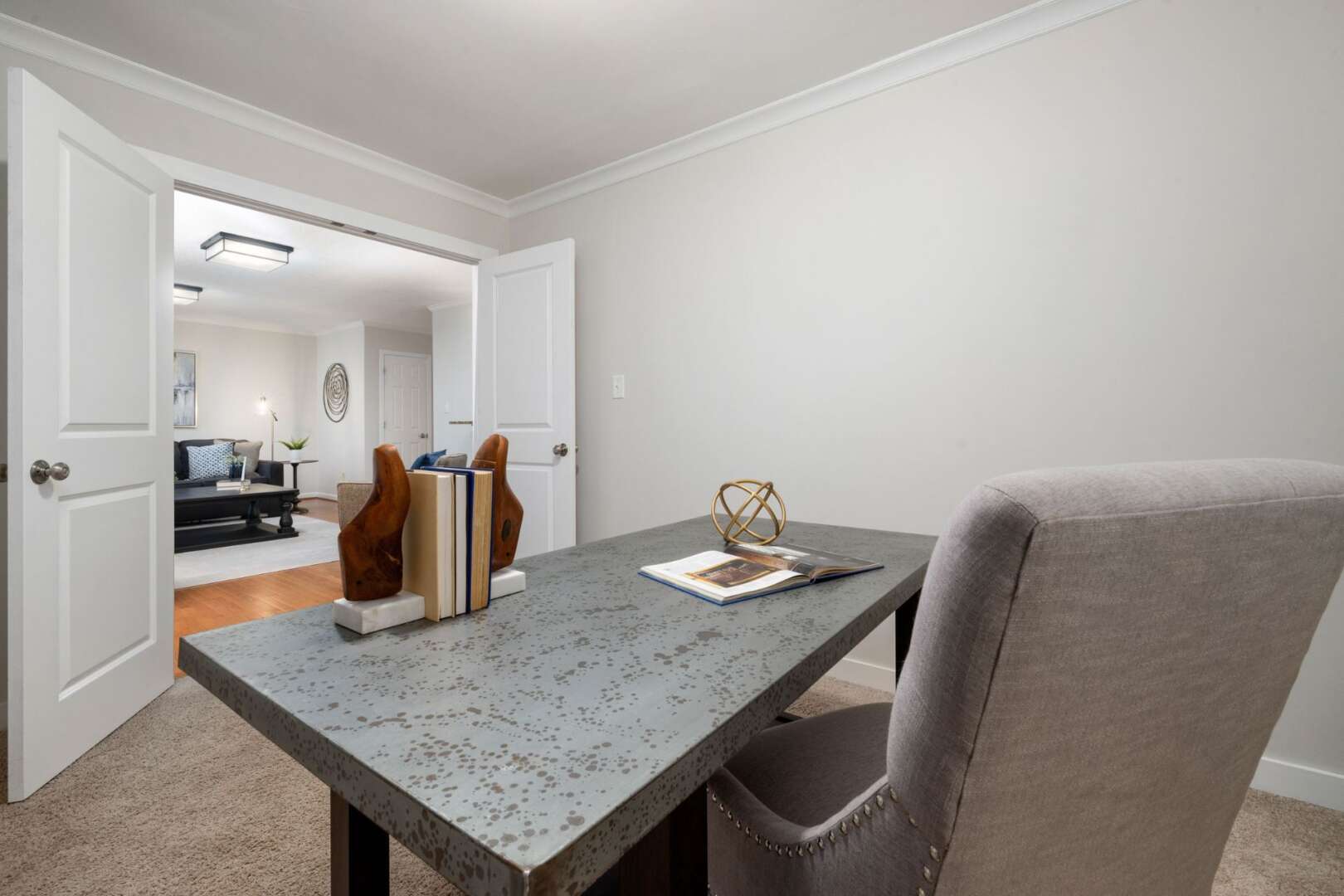 A newly renovated modern home office featuring a gray speckled desk and a beige upholstered chair.