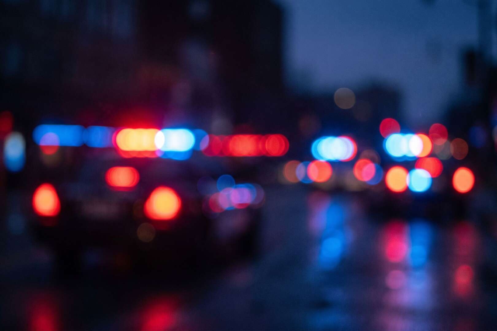 Blurred red and blue flashing lights from police cars at night.