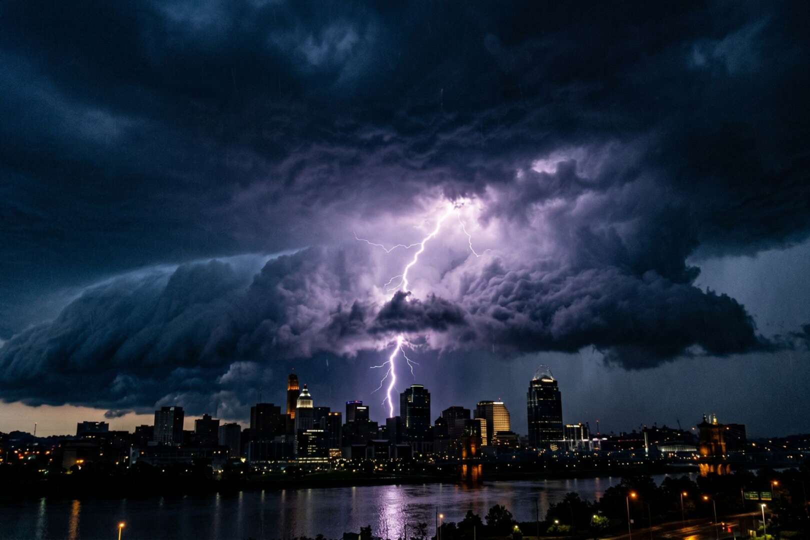 Dramatic view of lightning striking the Cincinnati skyline at night underneath dark, severe storm clouds.