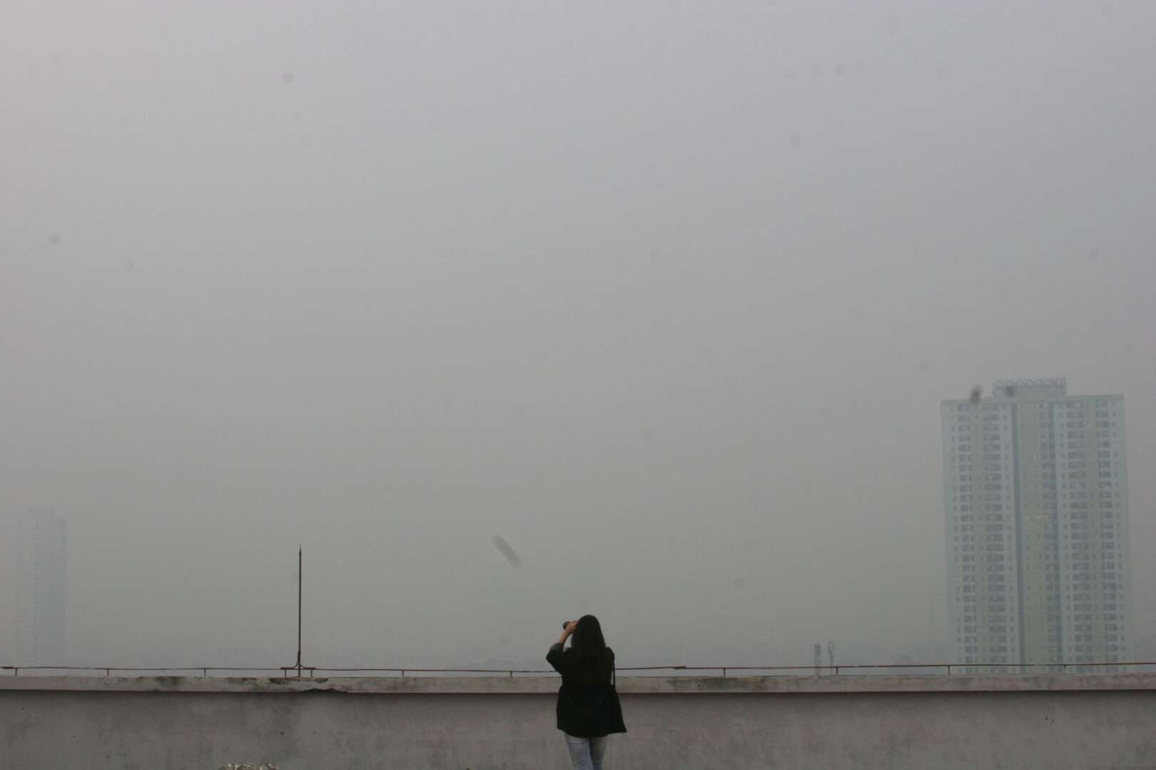 A person silhouetted against a hazy, smog-filled skyline during an air quality alert in Cincinnati.