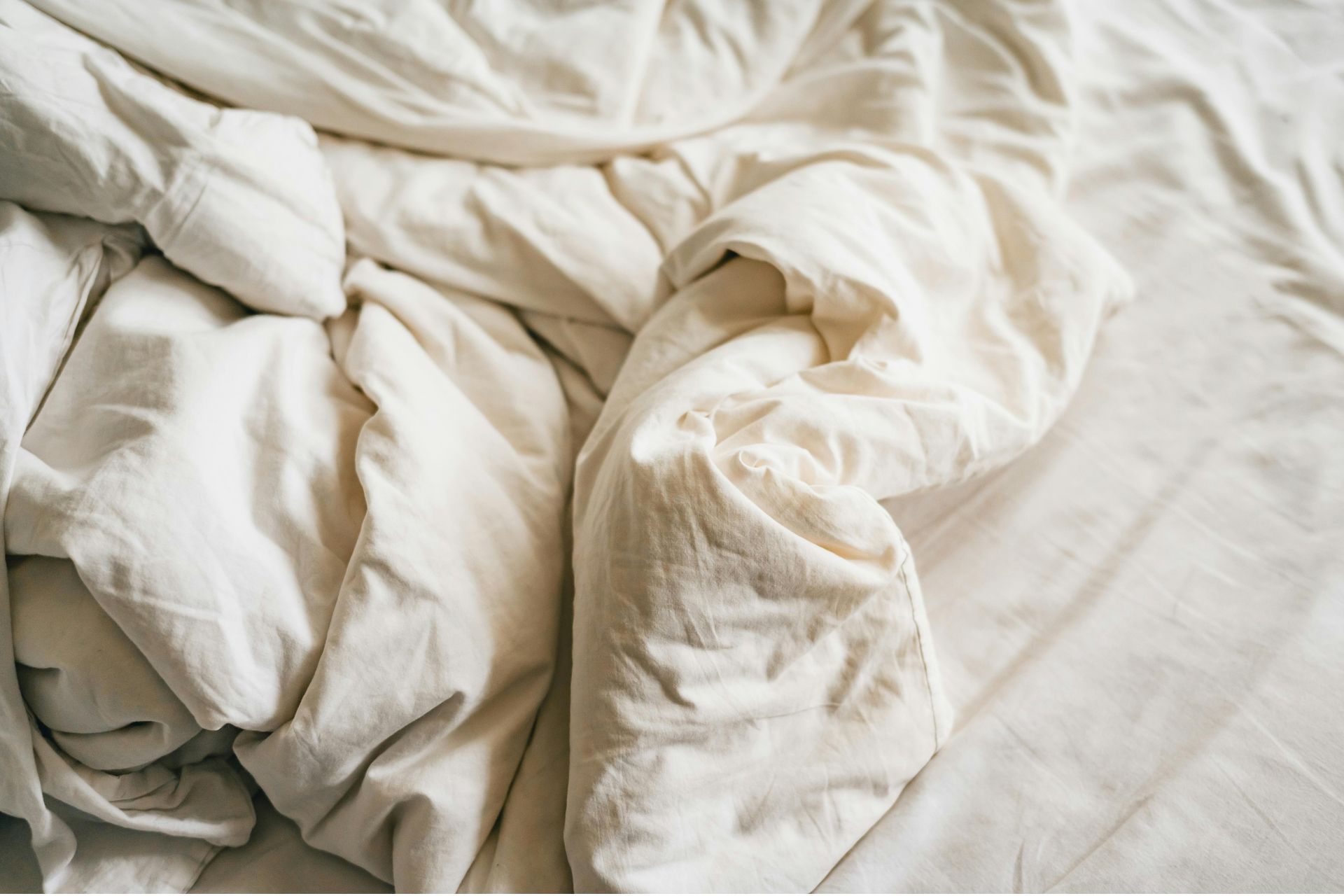 Unmade white bed sheets illustrating a potential bed bug infestation.