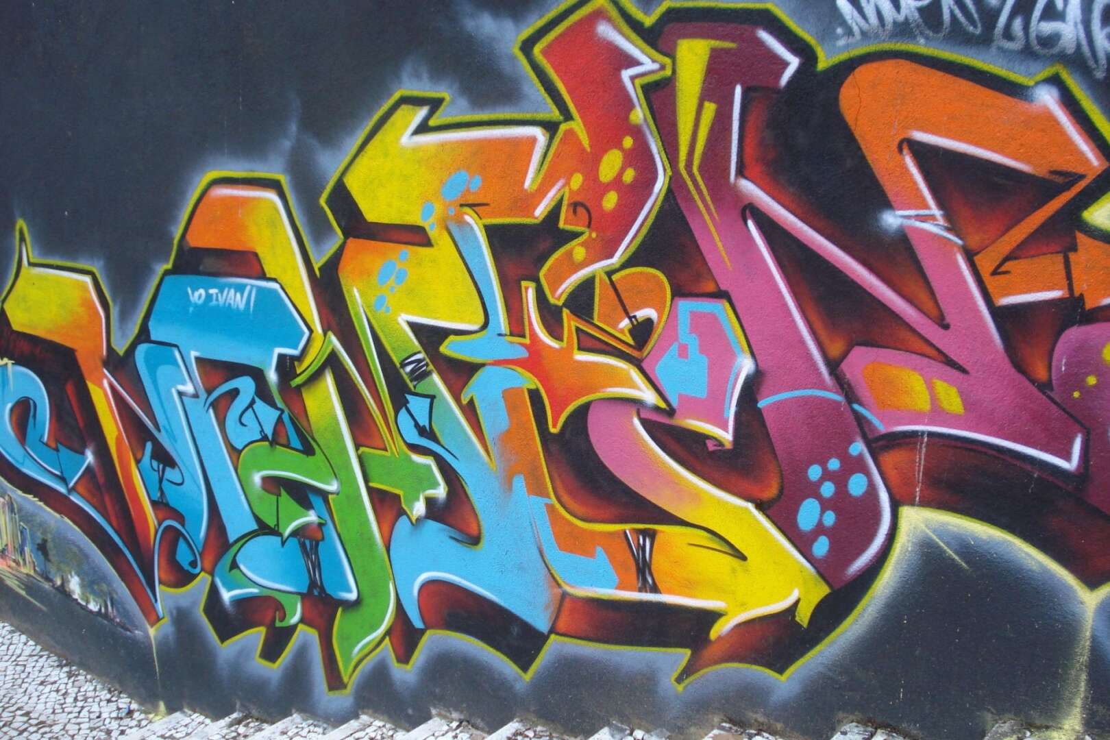 Colorful, stylized graffiti lettering spray-painted on a wall.