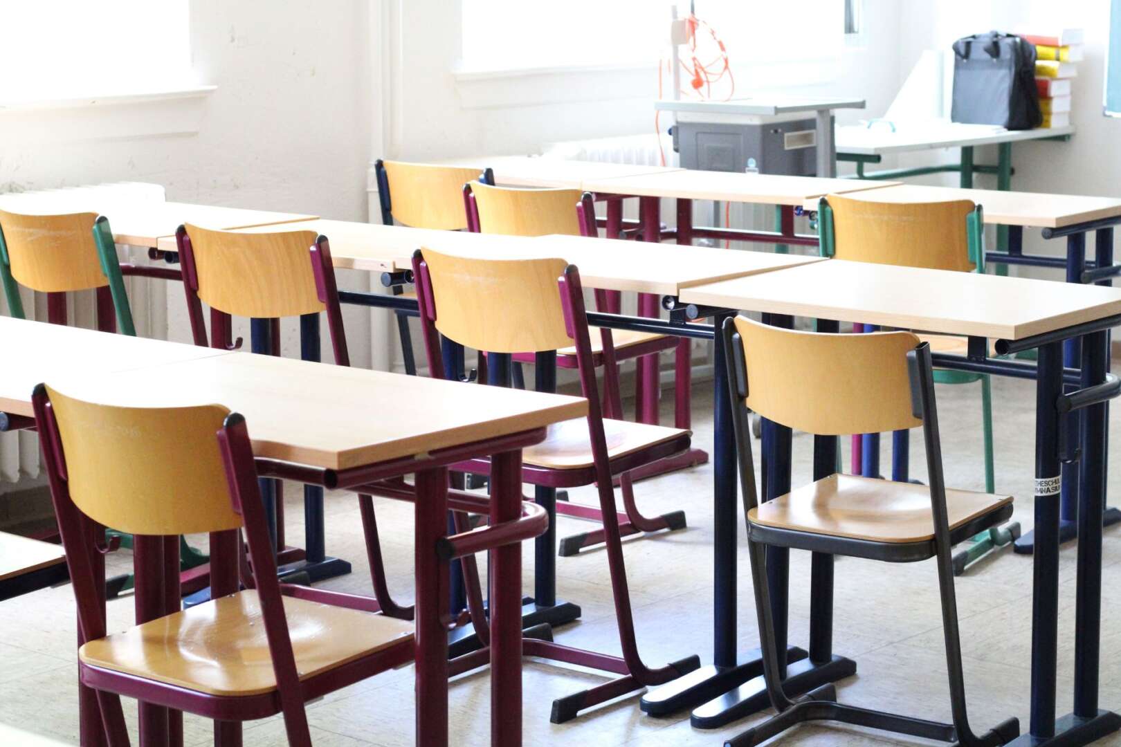 An empty classroom with rows of wooden desks and chairs.