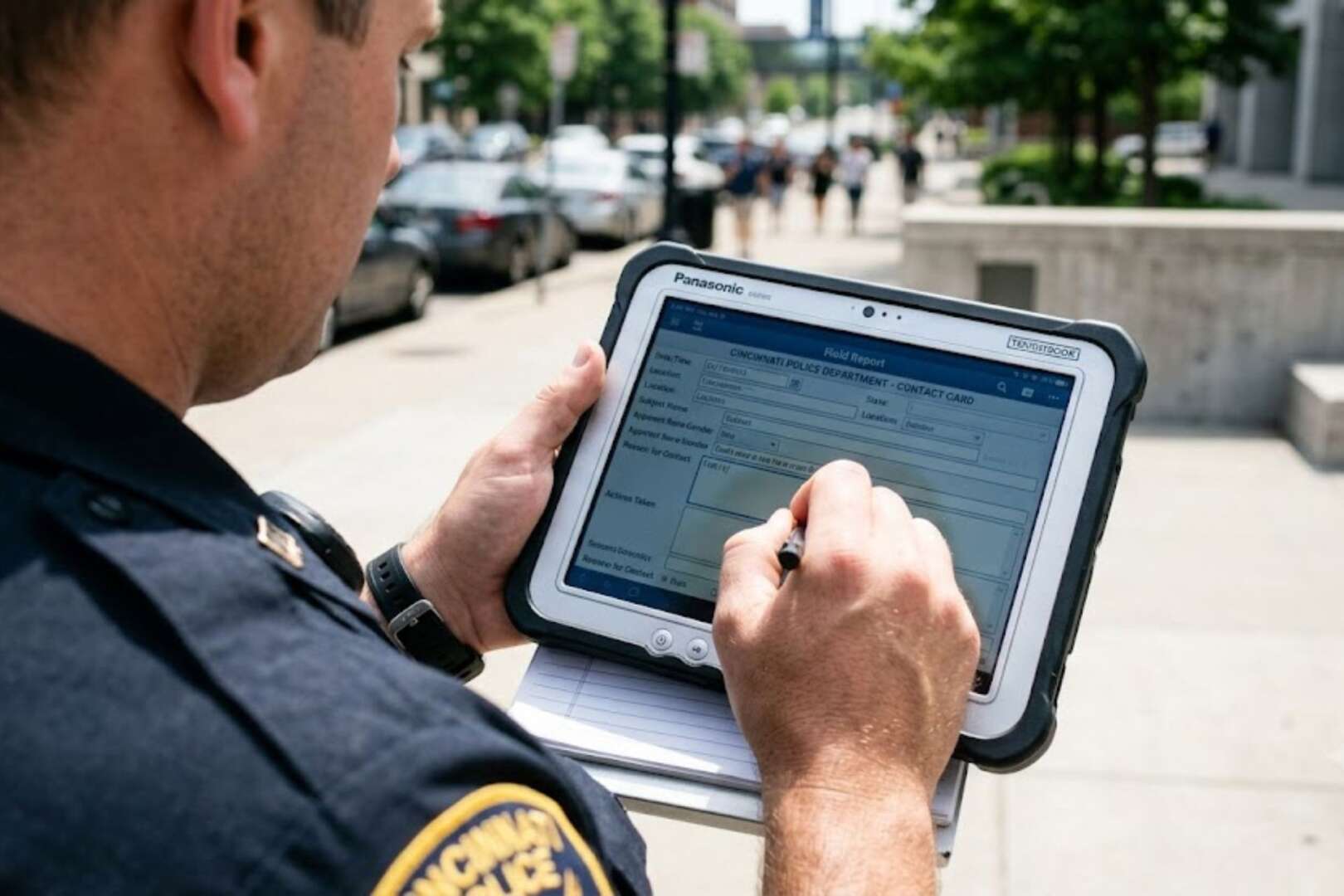 A police officer using a tablet device outdoors on a city street.