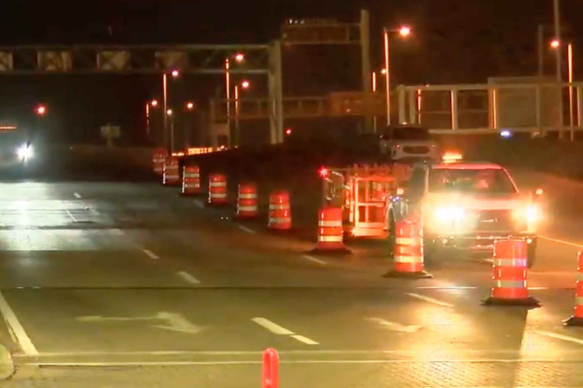 Nighttime view of orange traffic barrels lining Elm Street near Paycor Stadium during a downtown traffic pattern change.
