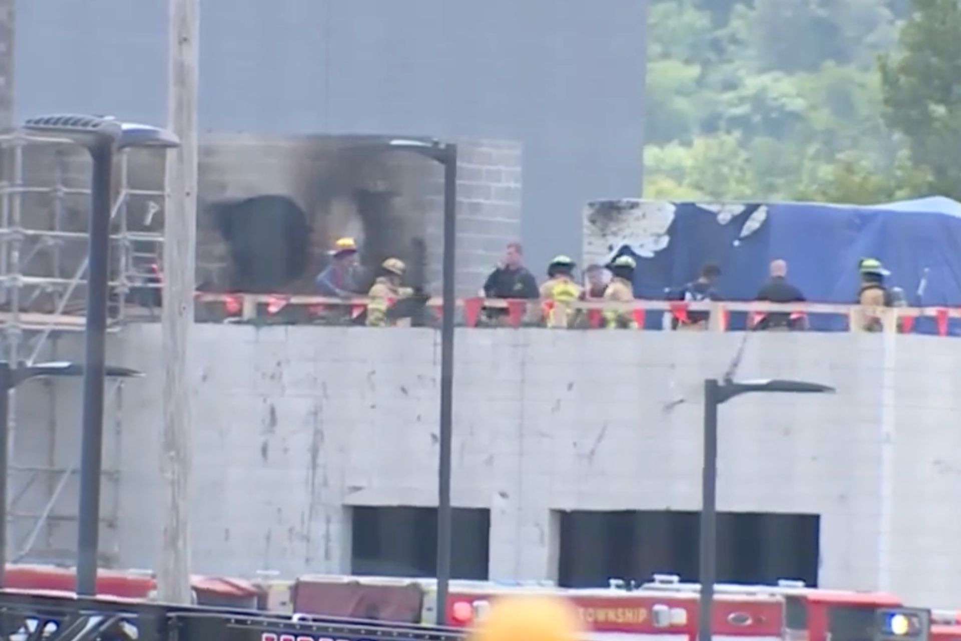 Emergency responders and firefighters on top of a concrete building under construction during a fire at the Farmer Music Center site.