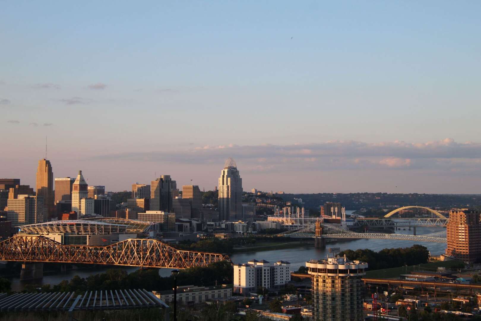 Distant aerial view of the Cincinnati skyline and the Ohio River during a hazy sunset.