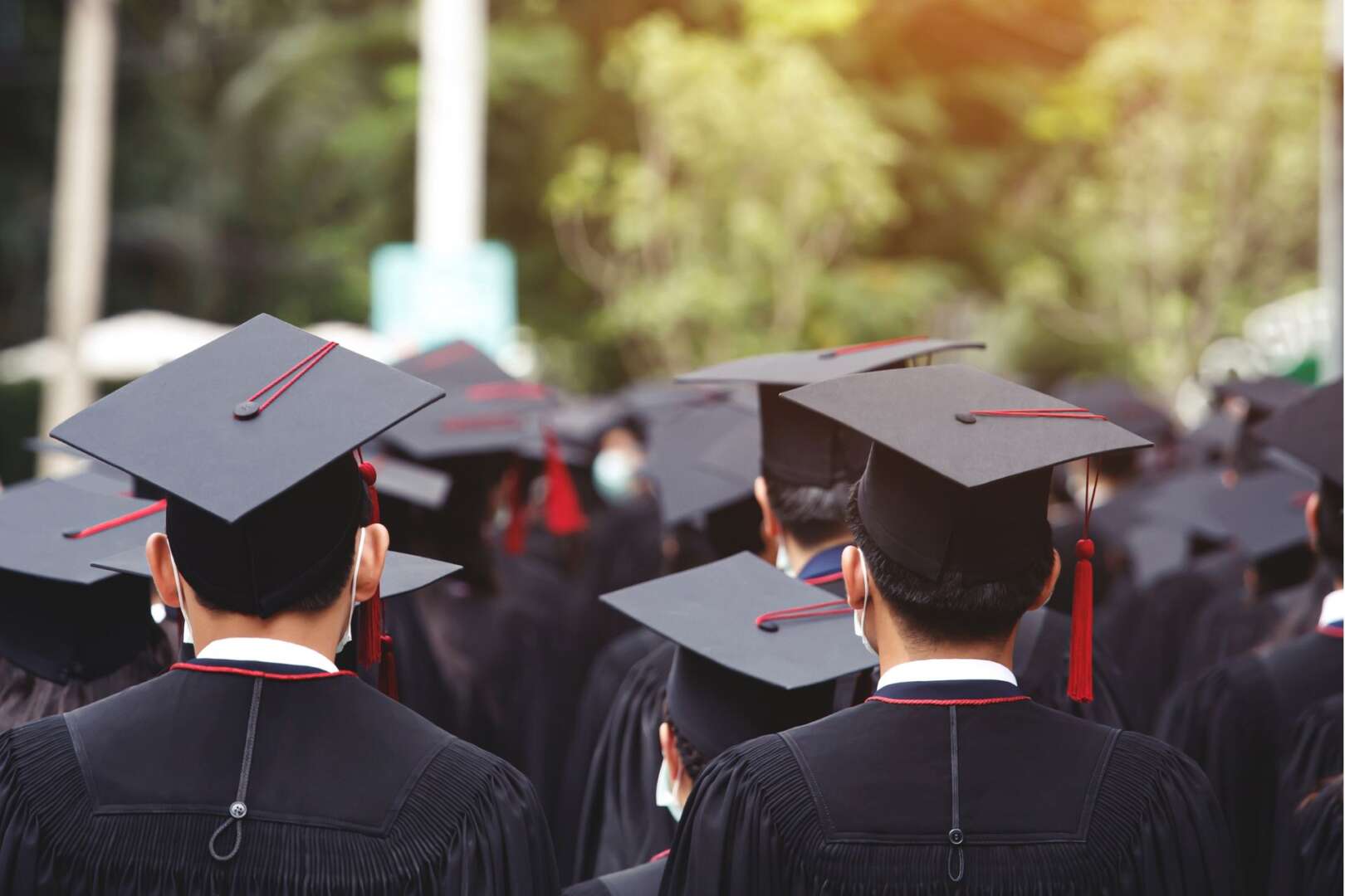 Graduates in black caps and gowns standing together at a commencement ceremony.