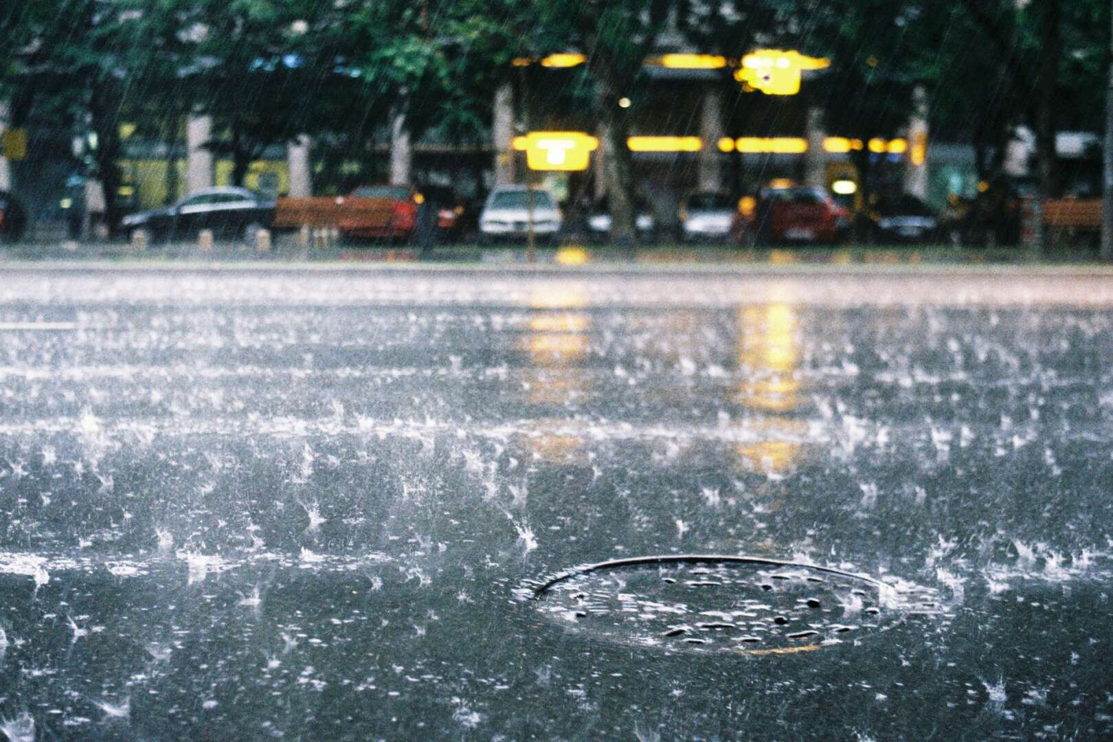 Heavy rain splashing on wet street pavement with reflections of city lights during a severe storm in Cincinnati.