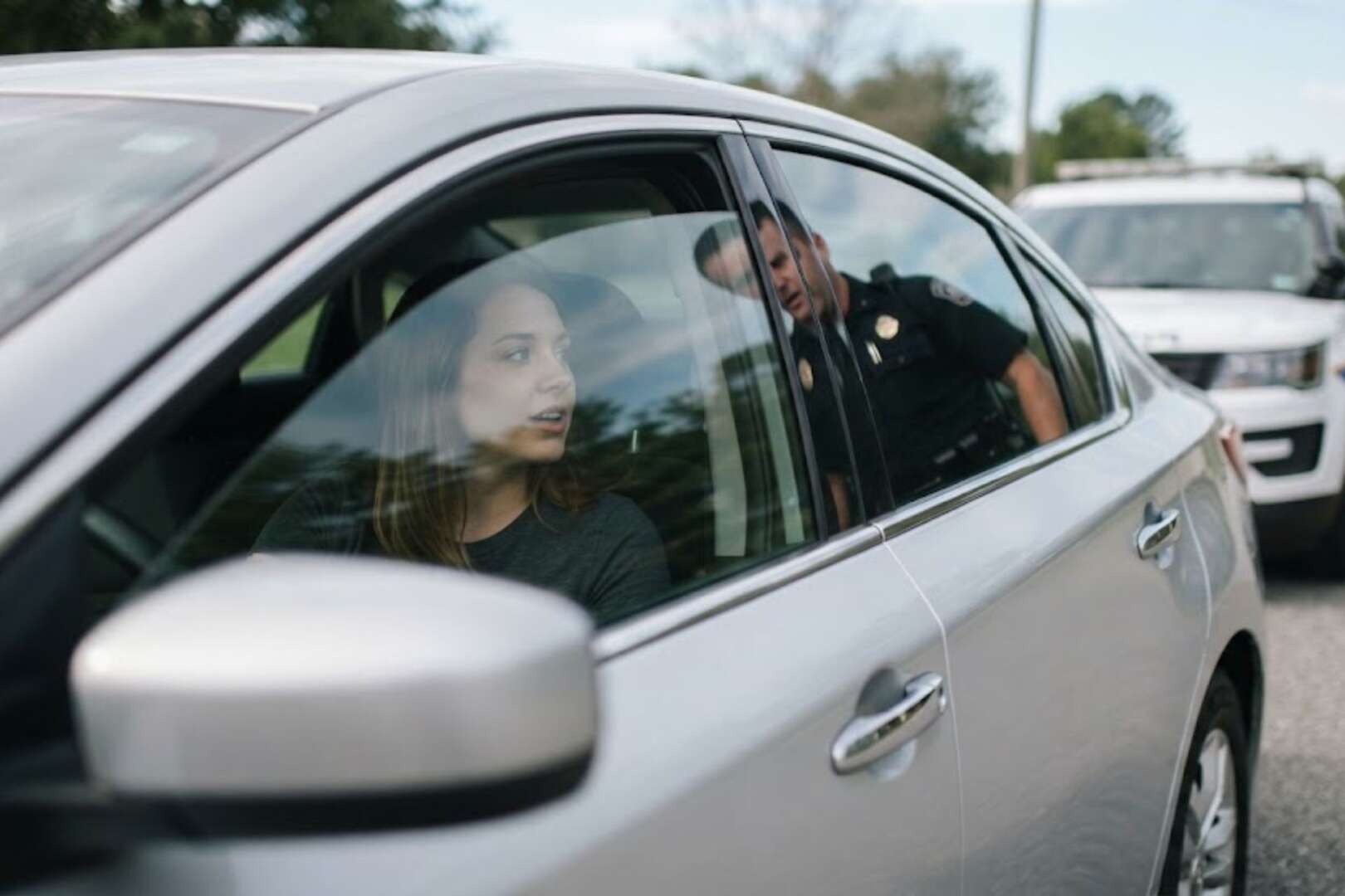 A police officer speaking to a driver through the window of a car during a traffic stop, illustrating the context of Ohio House Bill 492 identification requirements.