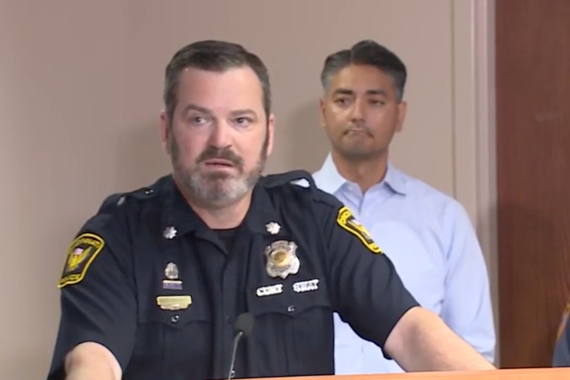 Police officer speaking at a podium during a press briefing regarding a Green Township shooting and abduction suspect
