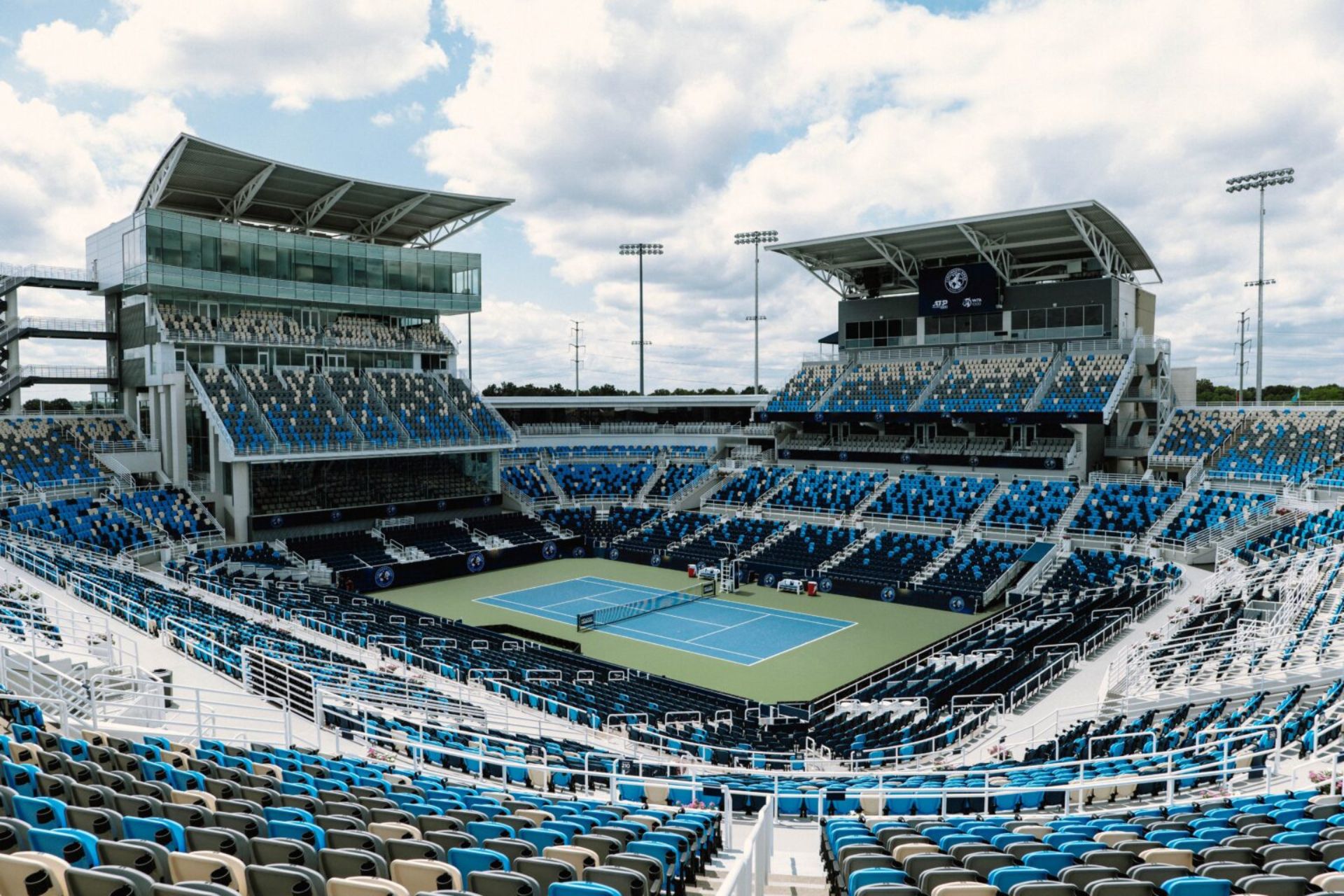Panoramic view of the Cincinnati Open outdoor tennis stadium court and seating stands under a blue sky.