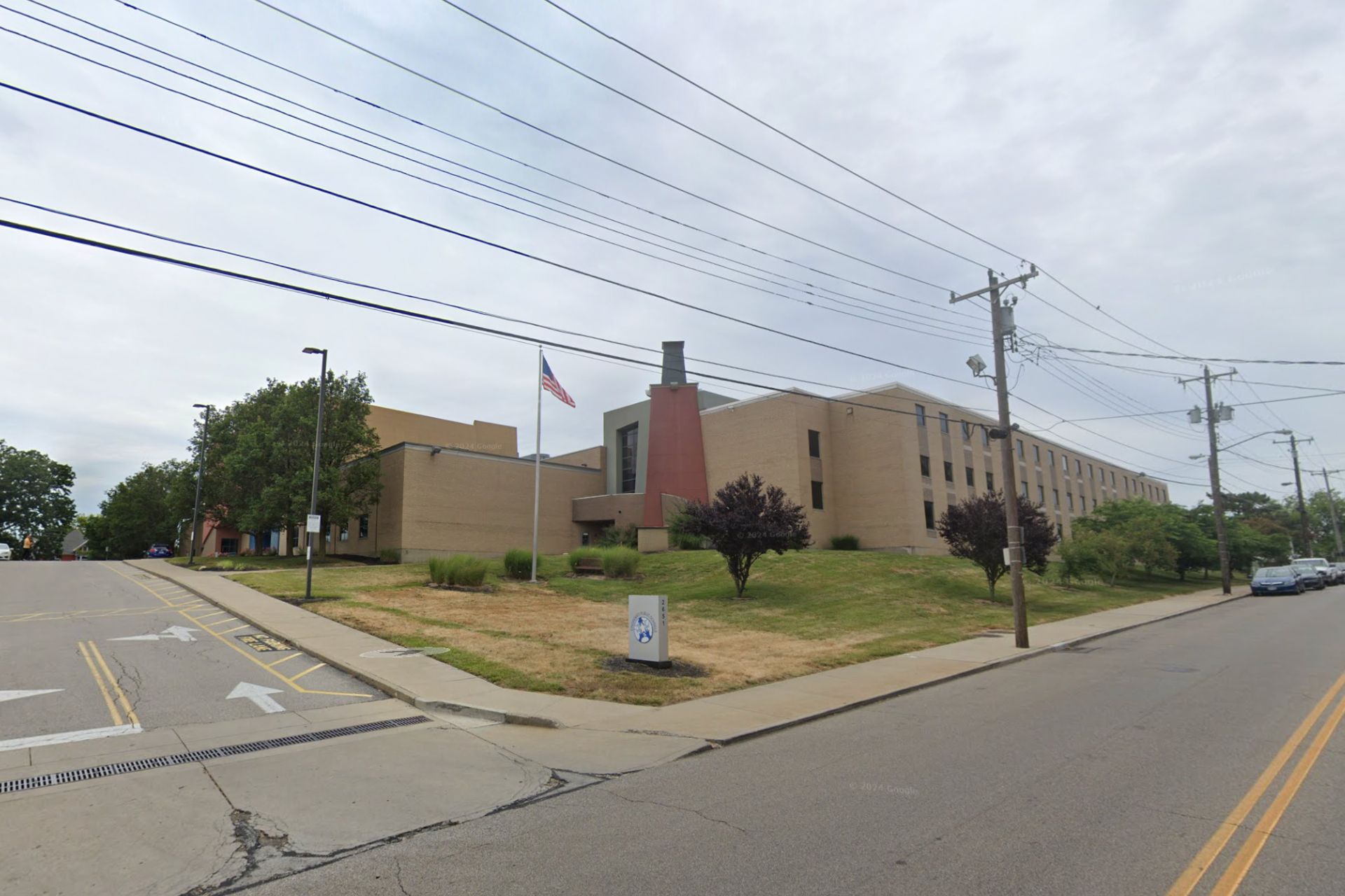 Exterior view of a Cincinnati Public Schools building with a grassy lawn and flagpole.
