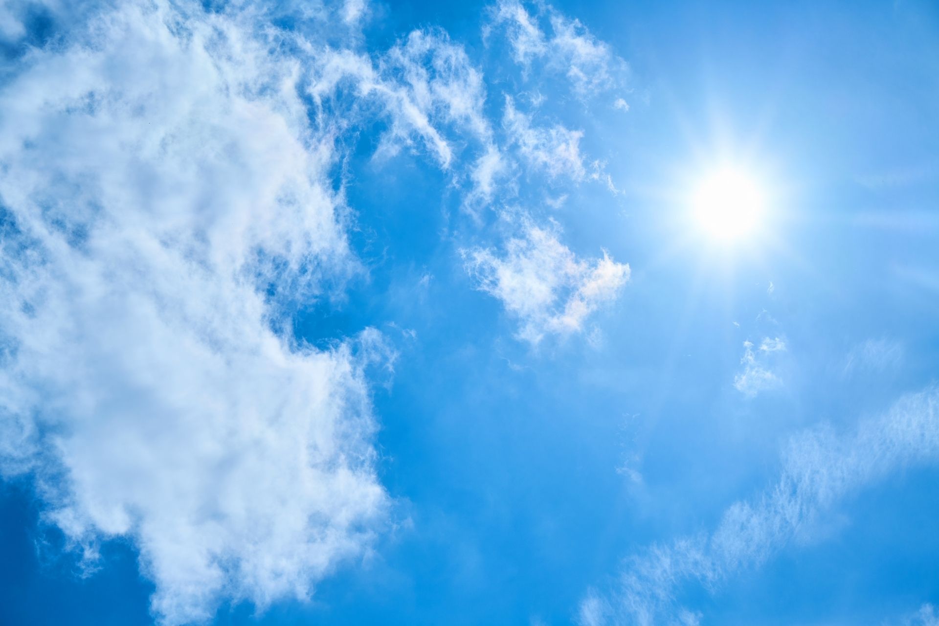 Bright blue sky with scattered white clouds and a radiant sun, illustrating the Cincinnati weekend weather forecast for August 29-30, 2026.
