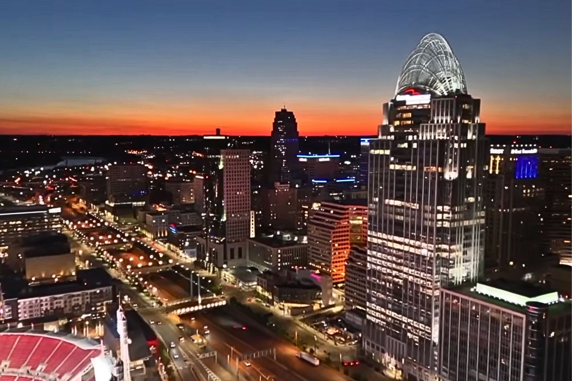 Aerial view of the illuminated downtown Cincinnati skyline and Great American Tower at sunset.