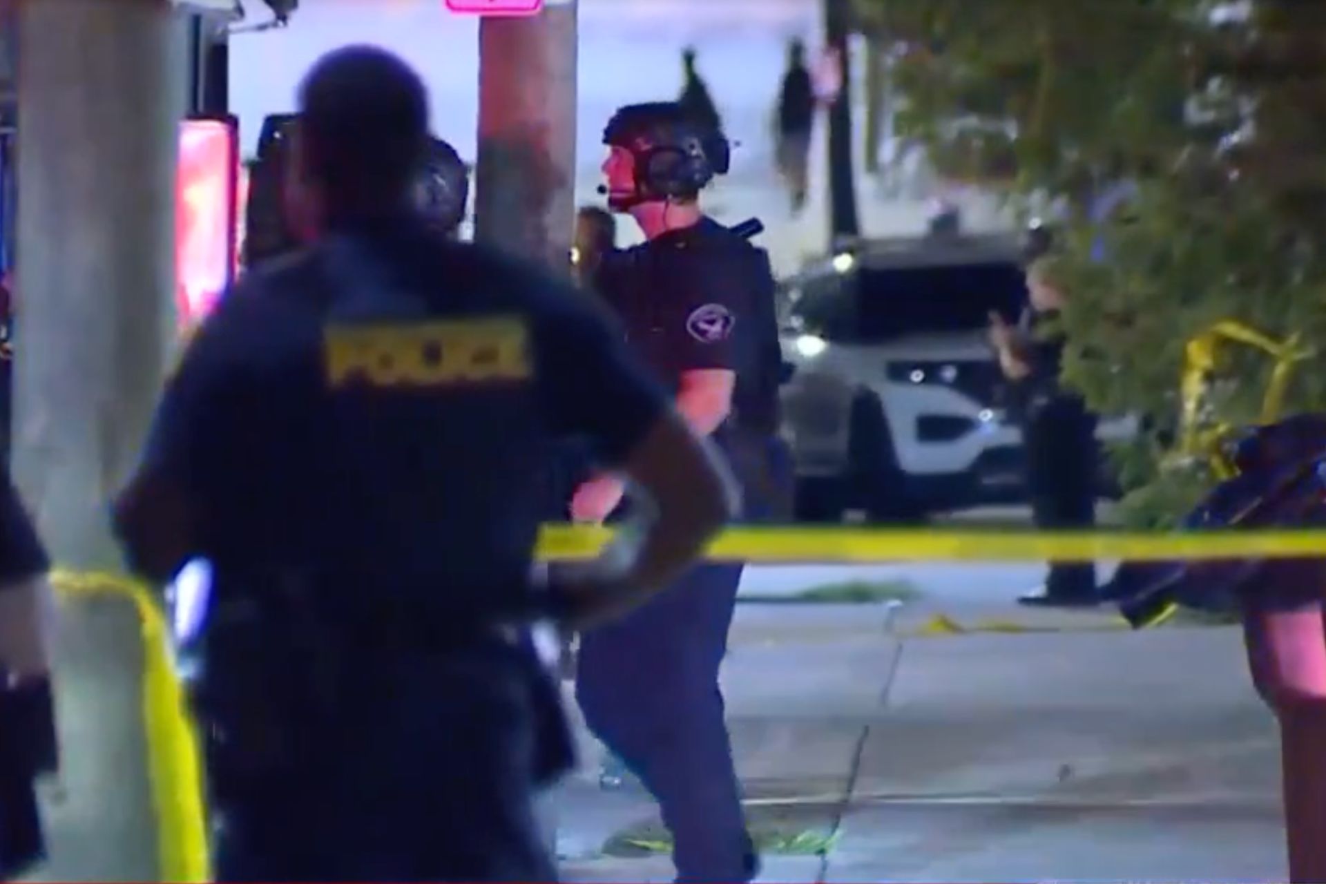 Police officers stand behind yellow crime scene tape at night during an active investigation in East Price Hill.