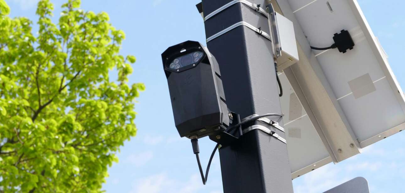 Flock license plate reading camera mounted on a pole with a solar panel.