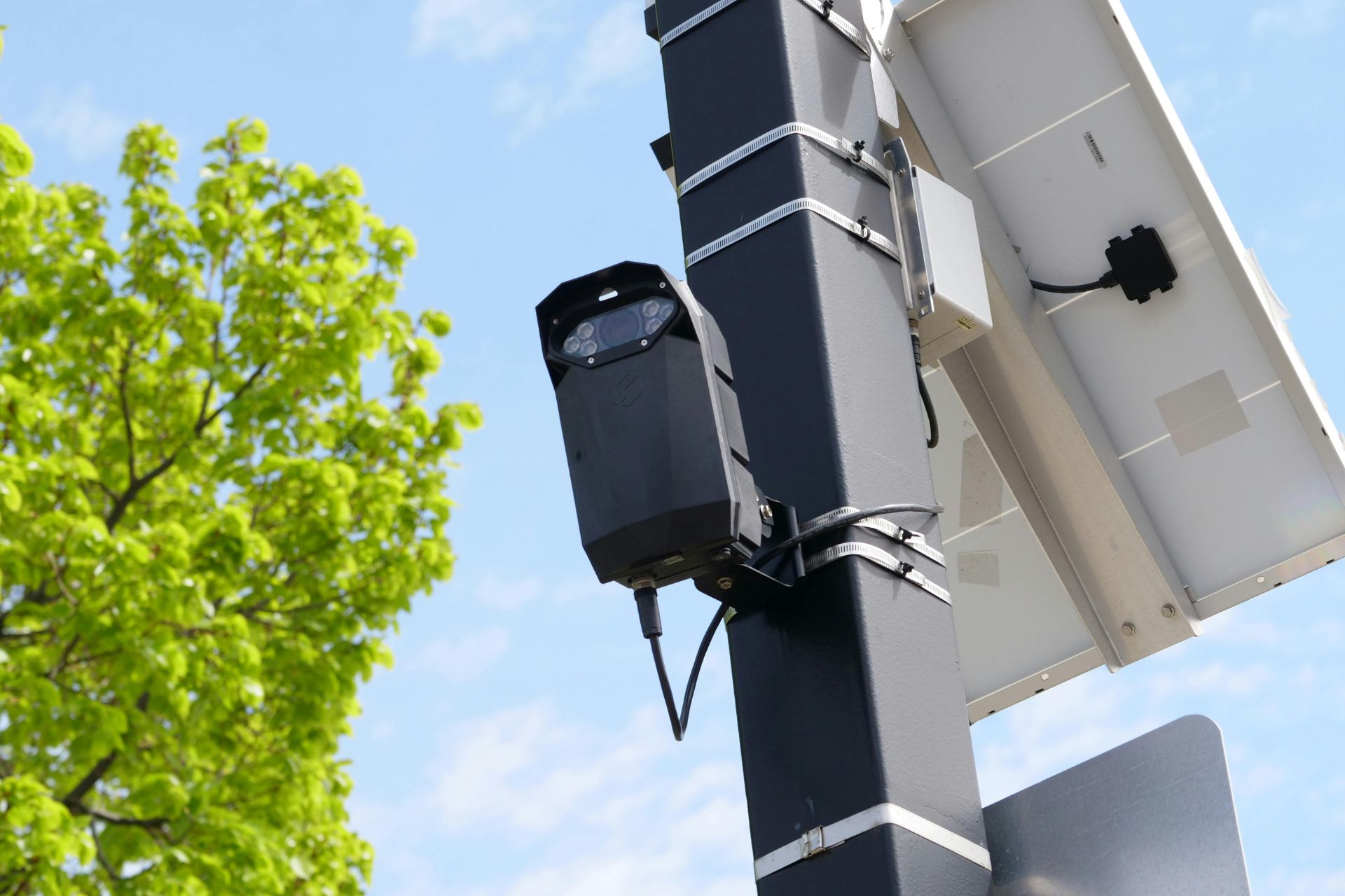 Flock license plate reading camera mounted on a pole with a solar panel.