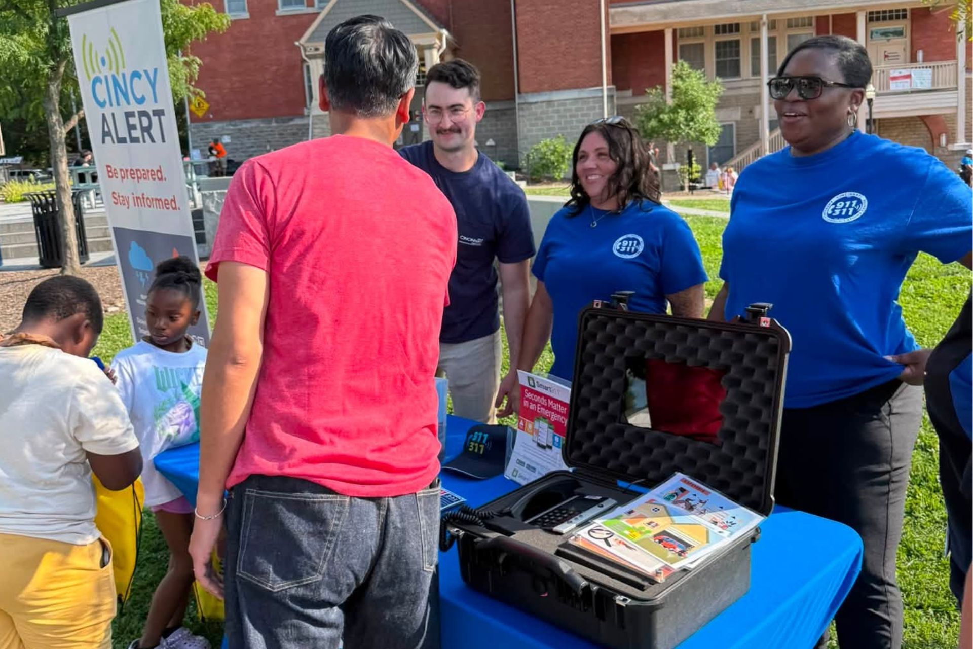Community members and event staff gather around an information table during a National Night Out event in Cincinnati.