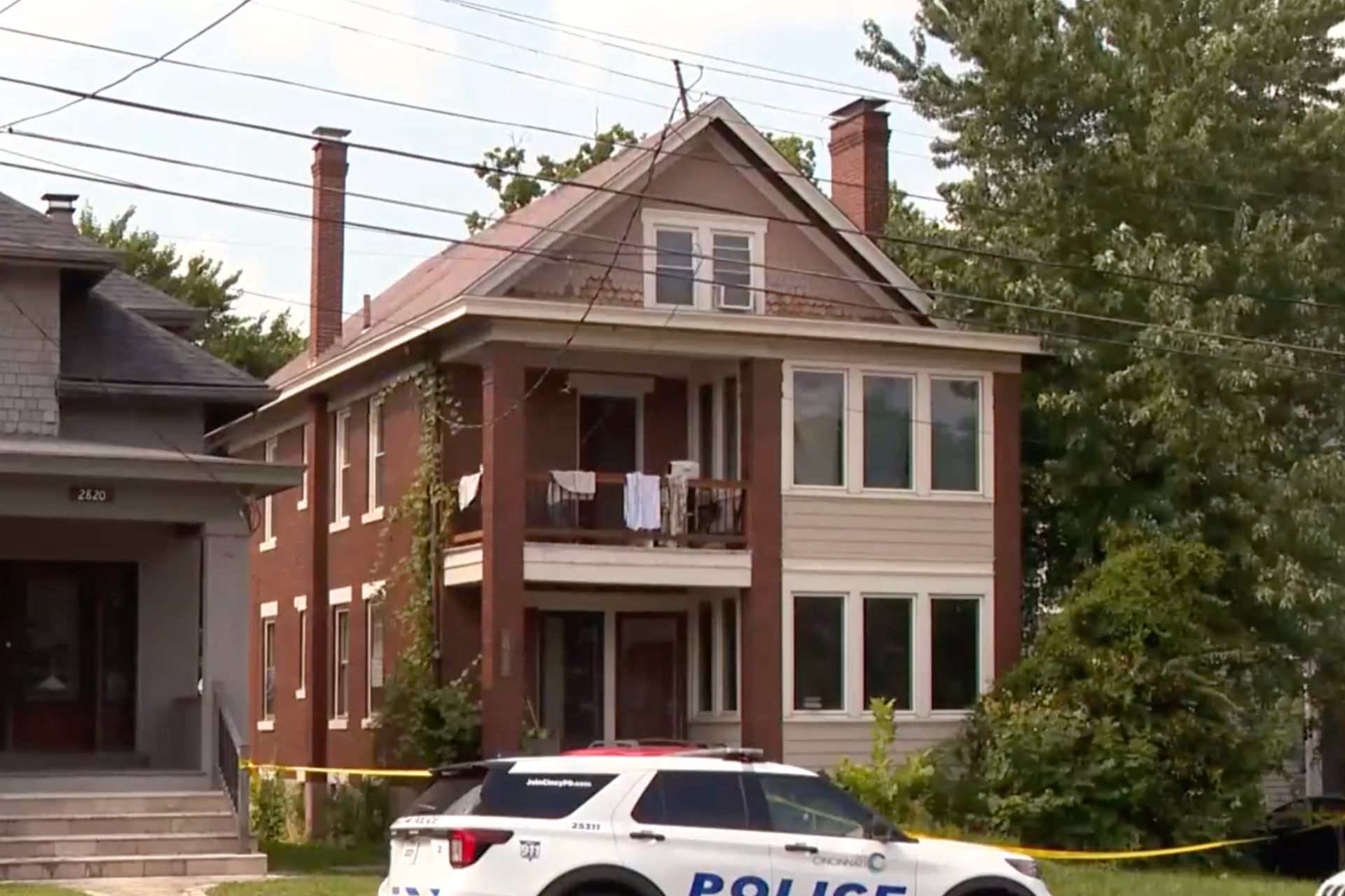 A police cruiser parked in front of a multi-story red brick residential house in Oakley.