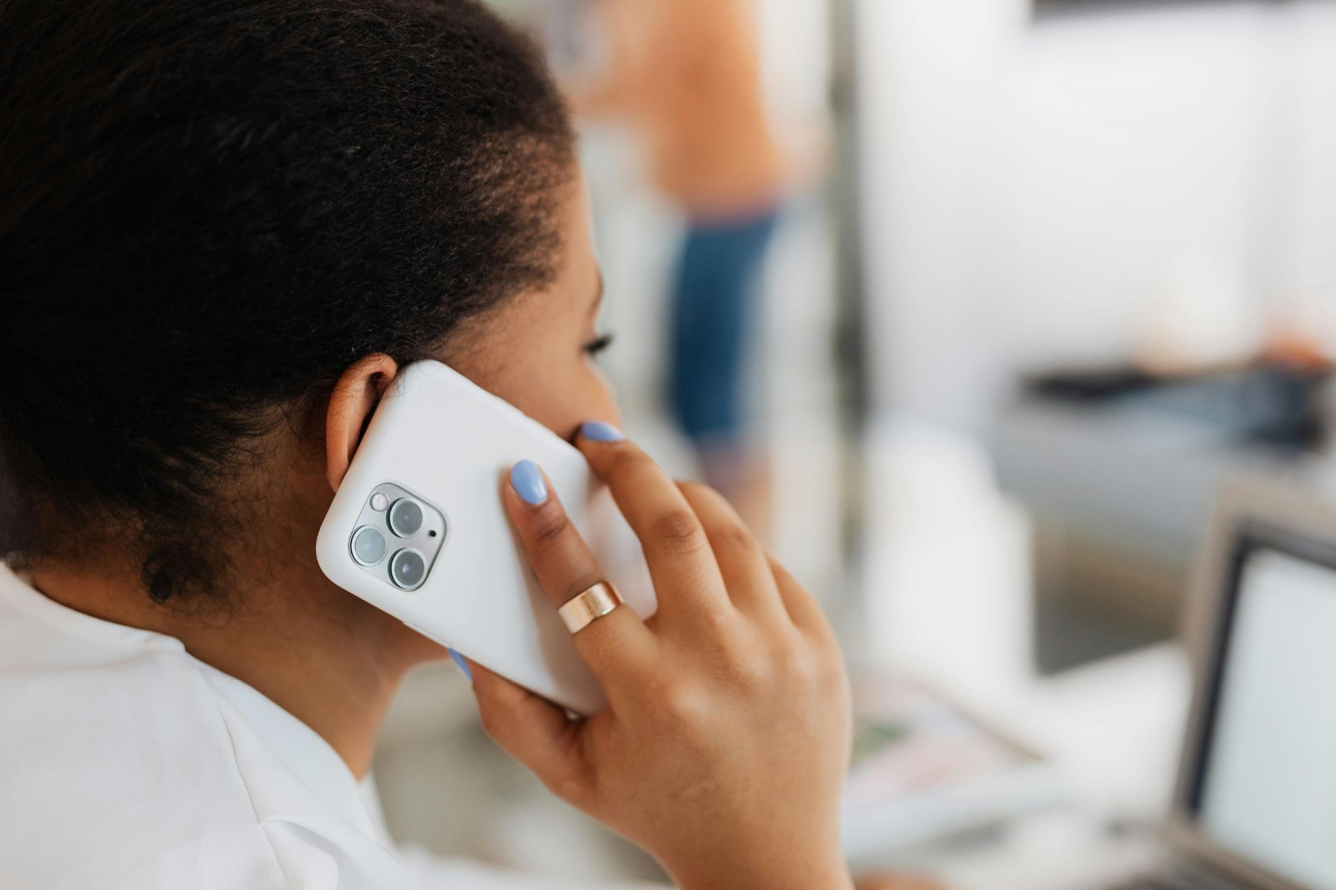 Woman holding a white smartphone to her ear during a phone call.