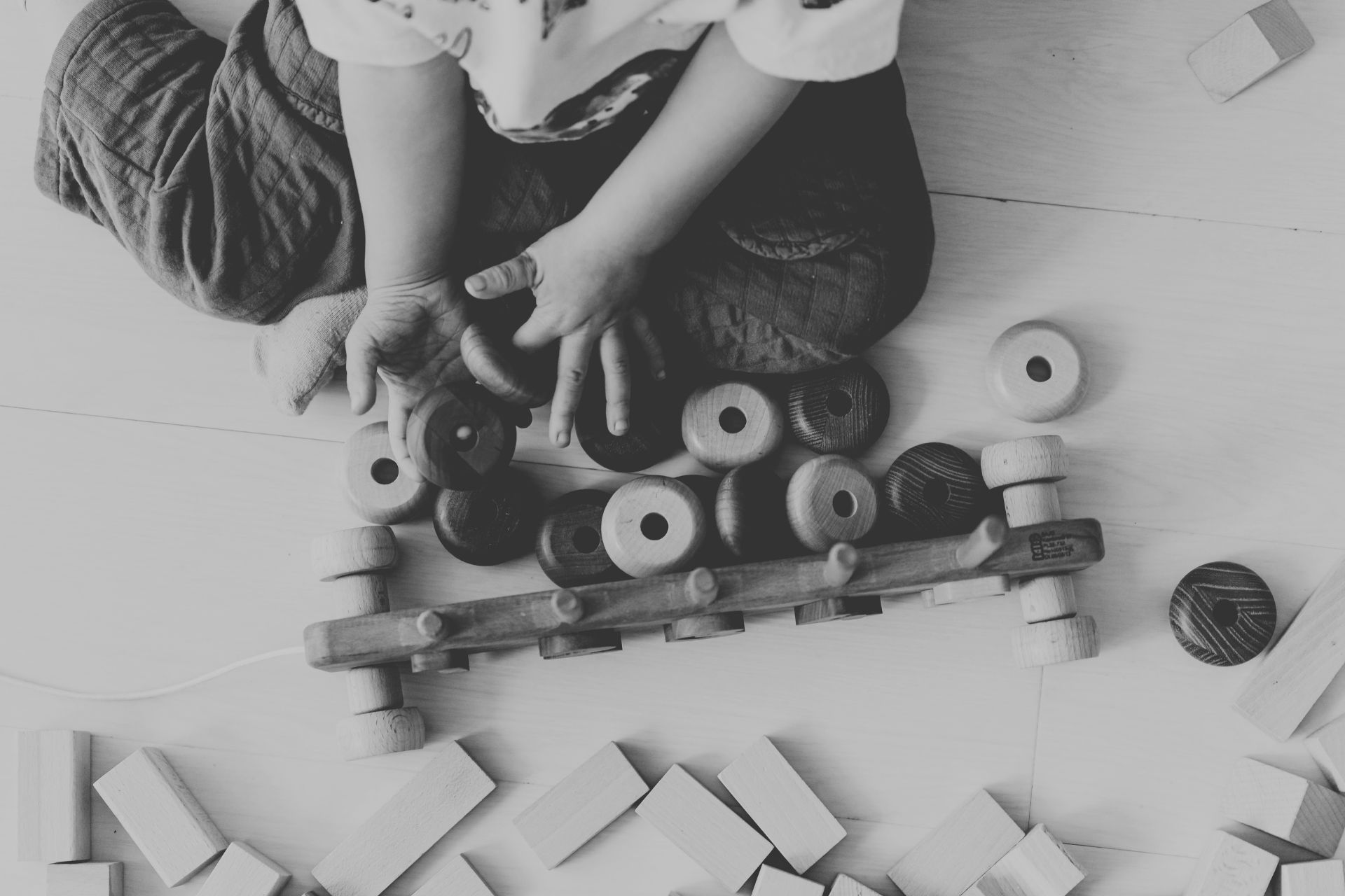 Child playing with wooden blocks on a floor.