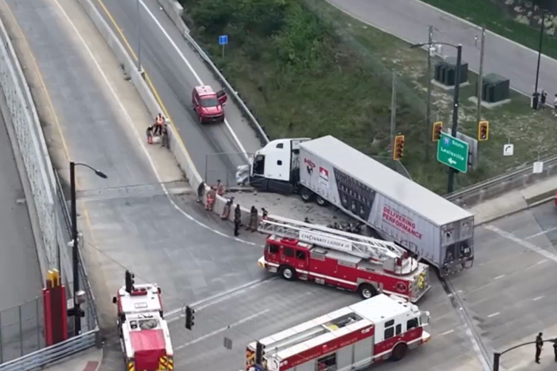 Aerial view of a jackknifed semi-truck crash blocking lanes on I-71 in Avondale, surrounded by responding fire engines.