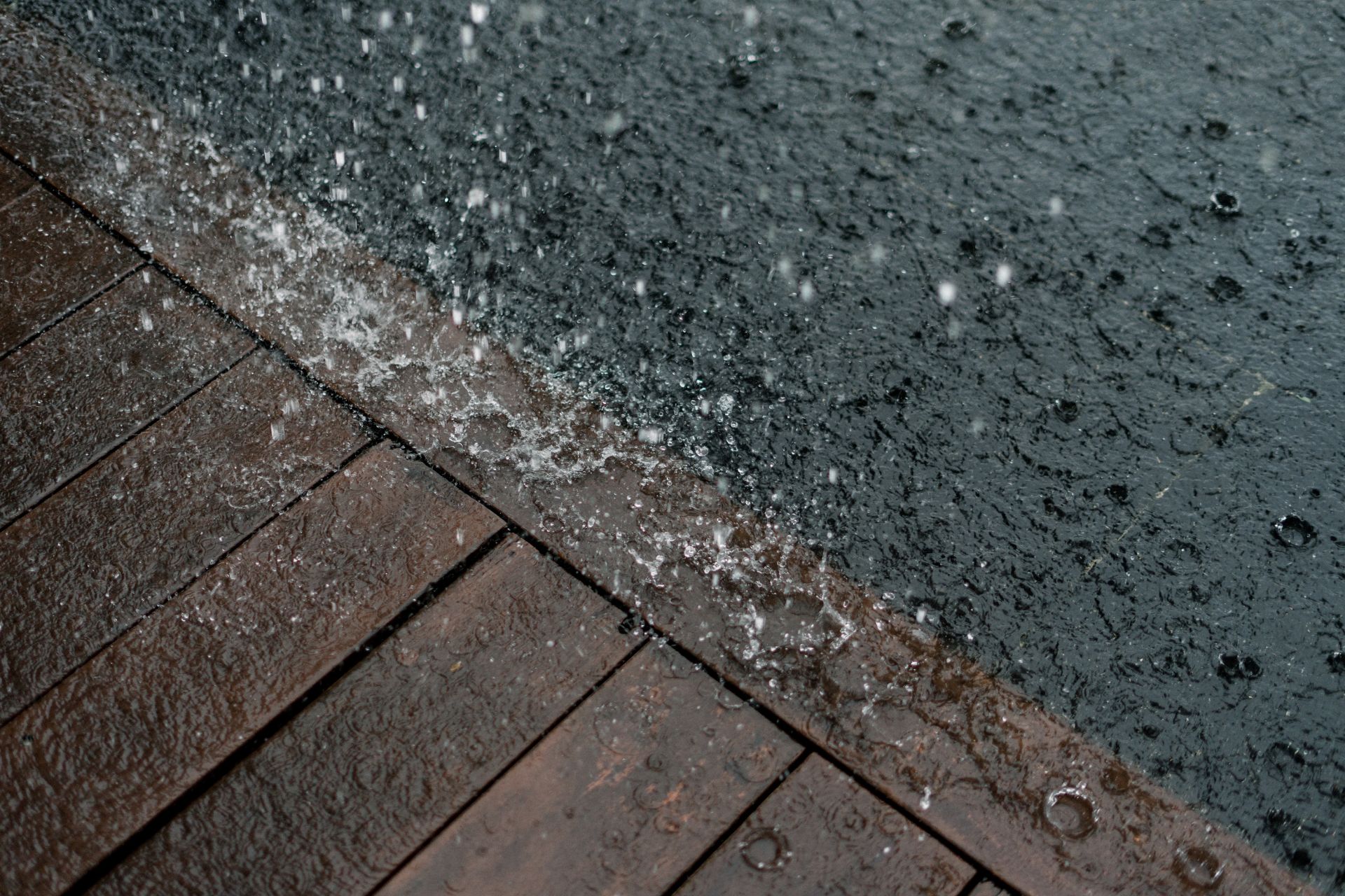 Heavy rainfall splashing on a wooden deck next to a pool during a slow-moving Cincinnati storm.