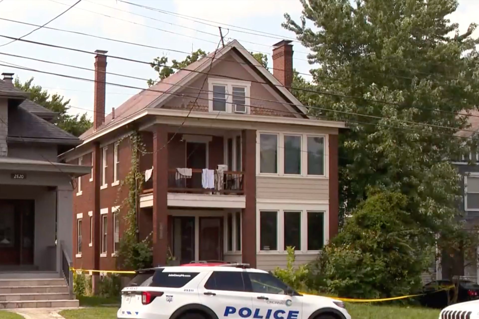 A police car parked in front of a two-story brick and wooden residential building.