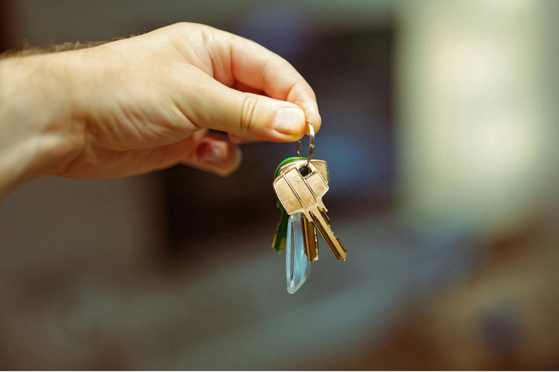 A hand holding out a set of apartment keys on a keyring, representing new workforce housing in North College Hill.