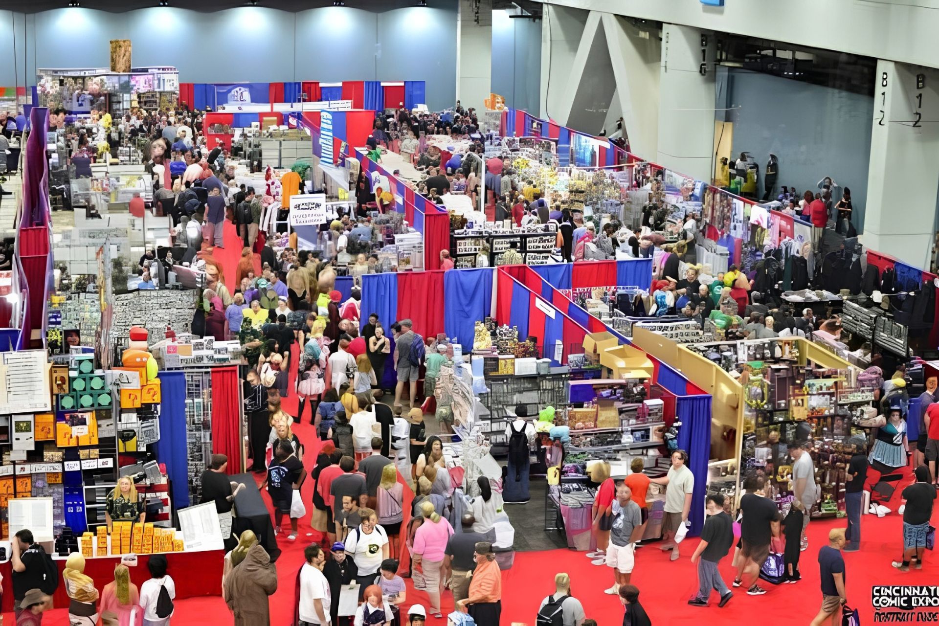 An overhead view of a busy convention center floor at the Cincinnati Comic Expo, showing large crowds of attendees walking among vendor booths.