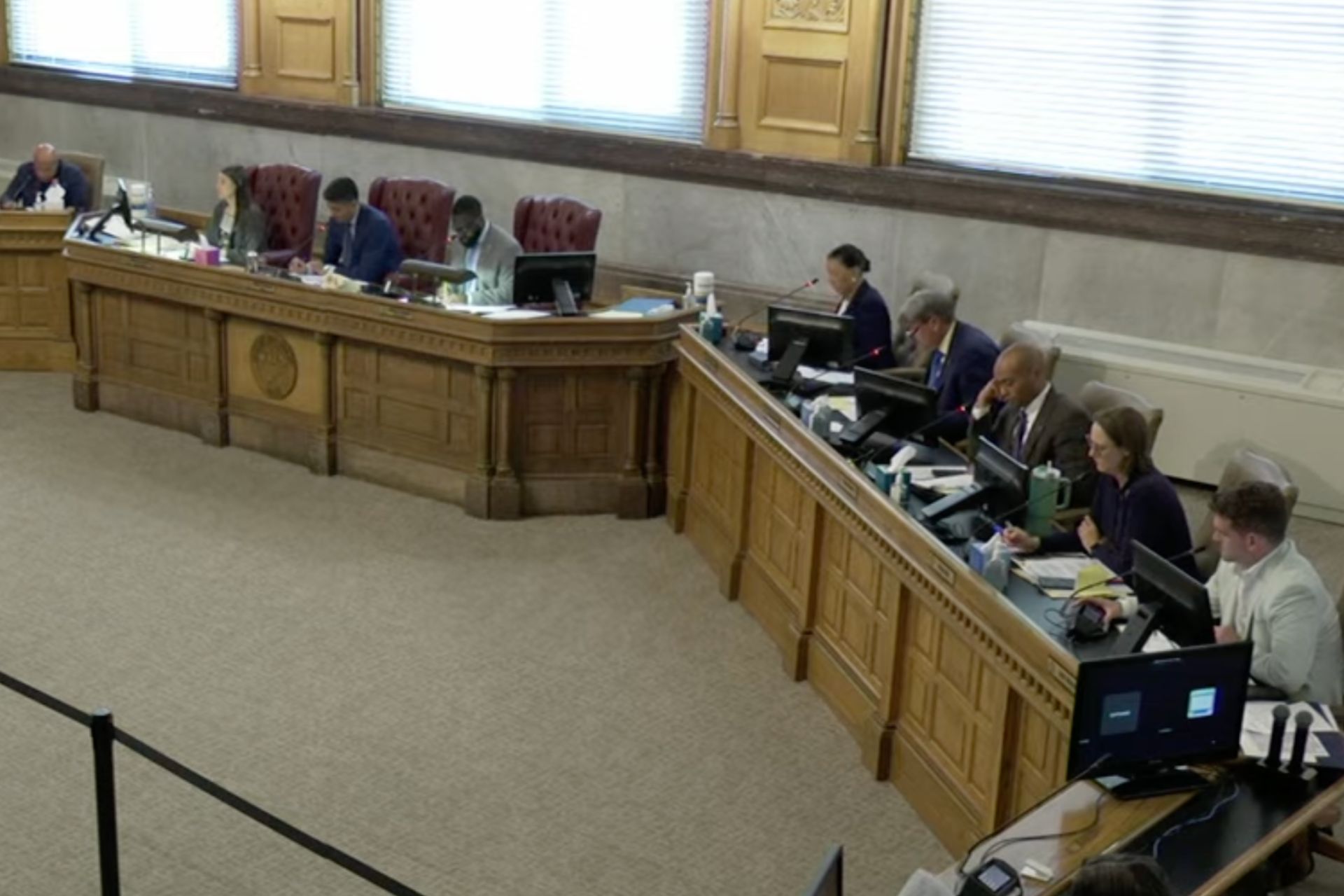 High-angle view of city officials seated at a curved dais during a Cincinnati flood response review meeting.
