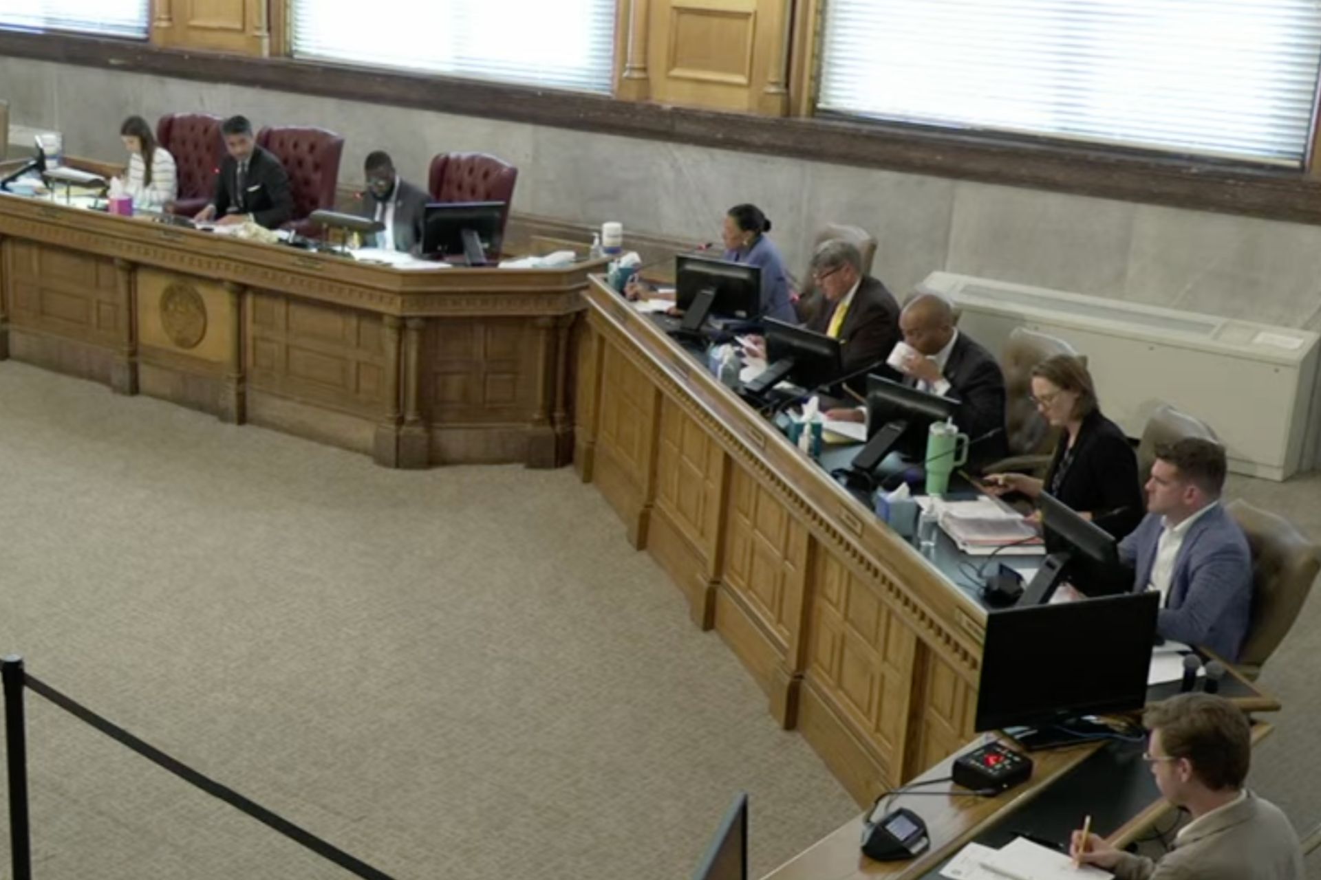 Cincinnati city council members seated at a curved wooden dais during a meeting on parking security requirements.