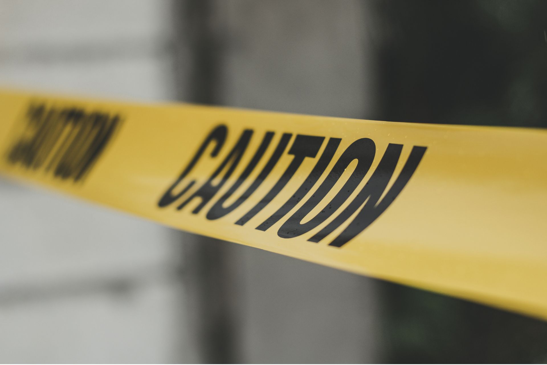 Yellow caution tape stretched tightly across a restricted area with a blurred background.