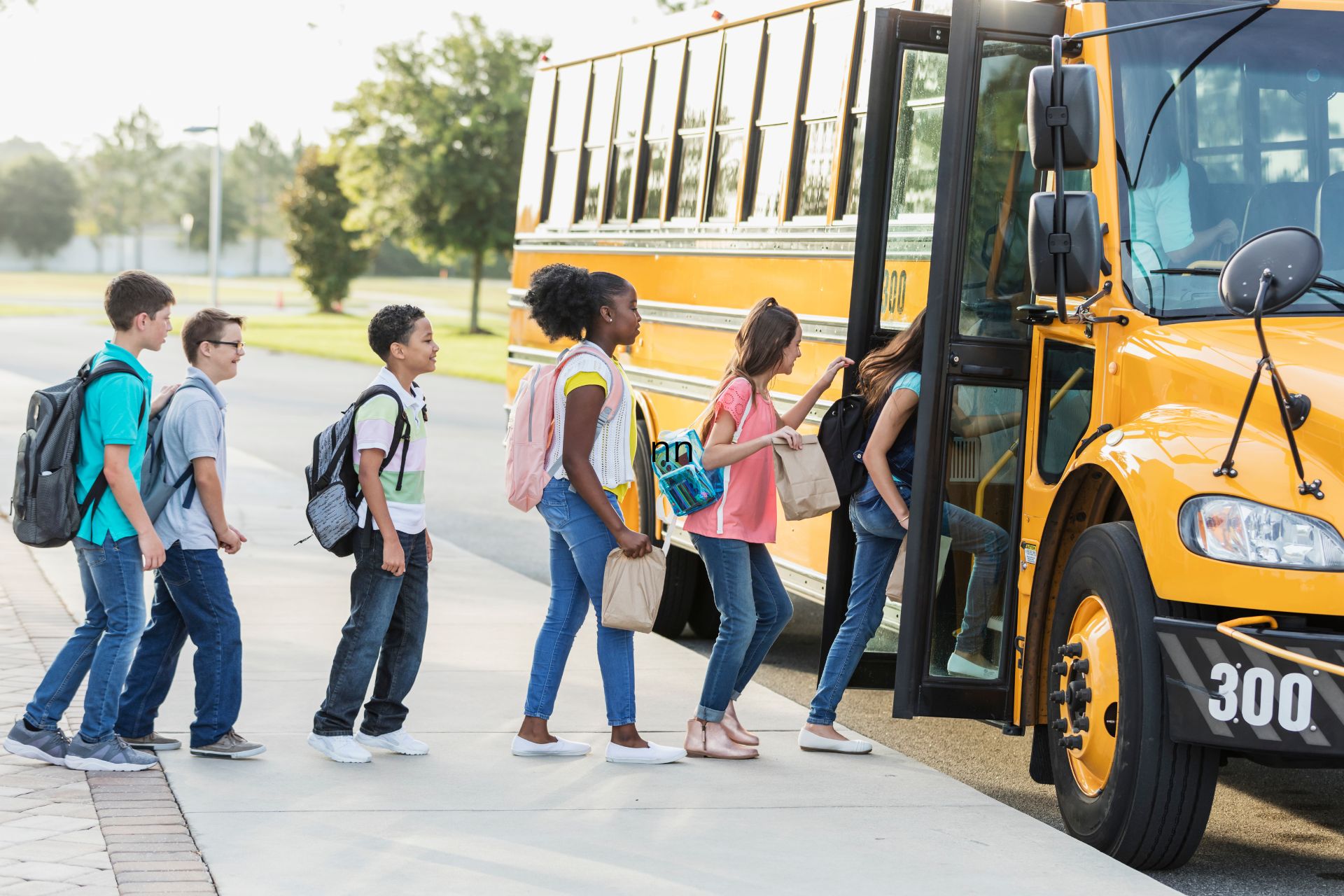 Students with backpacks boarding a yellow school bus.