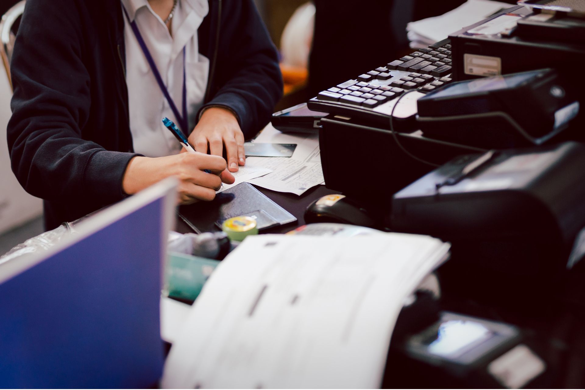 Hands reviewing financial documents and paperwork at a bank teller desk.