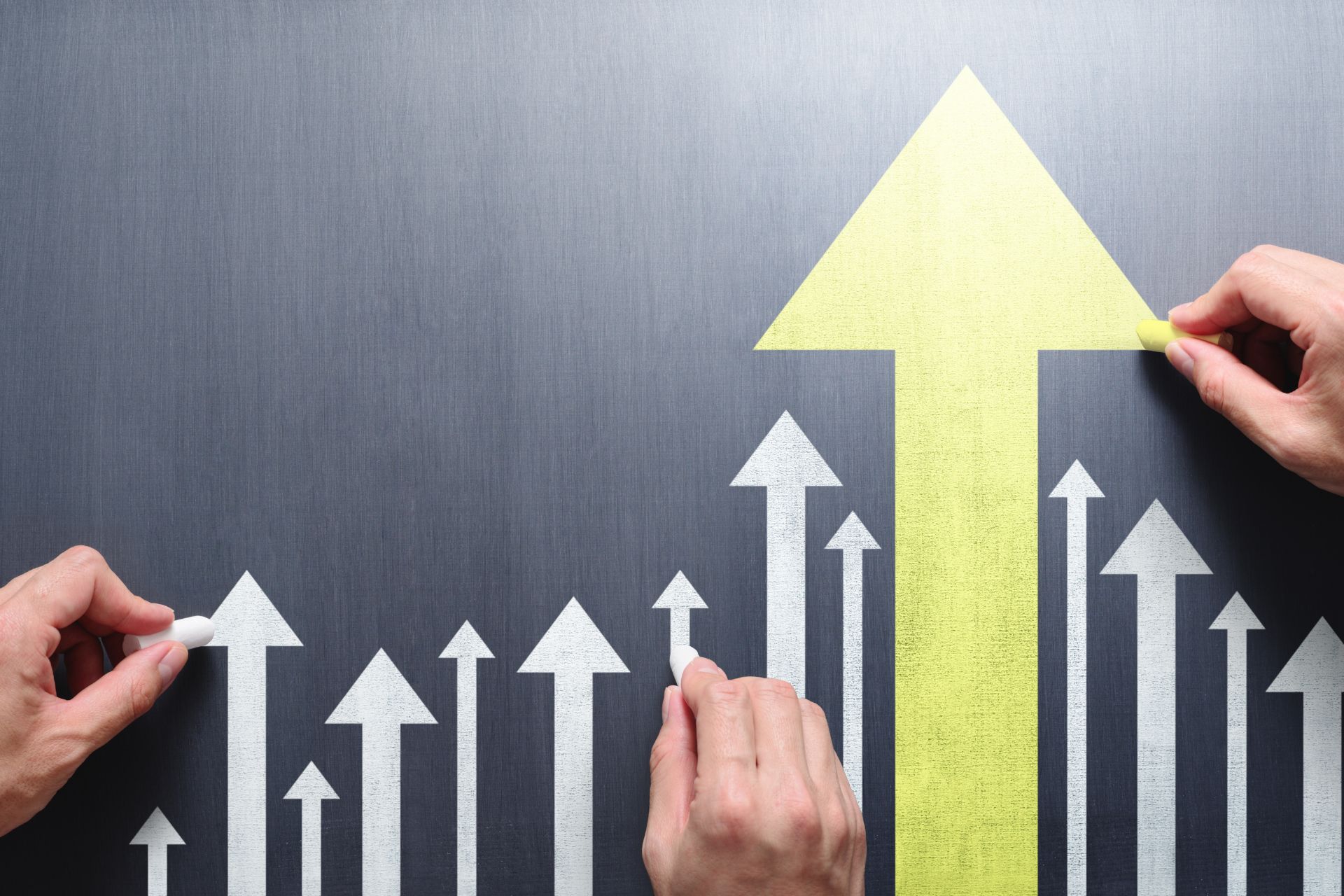 Hands placing upward-pointing arrows on a dark surface, featuring a prominent yellow arrow in the center.