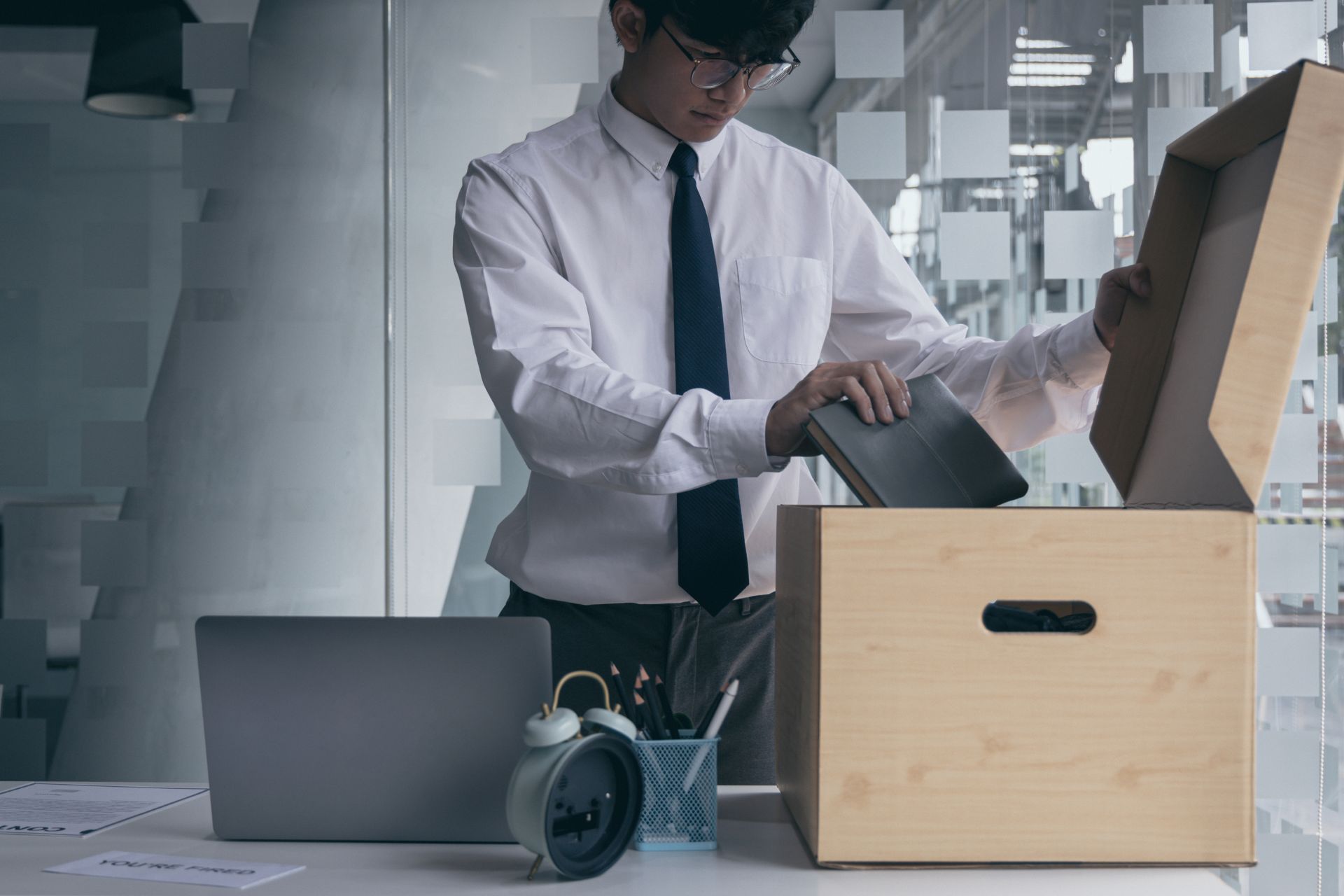 An office worker packing personal belongings into a cardboard box on a desk, representing job losses and workforce layoffs in Ohio.