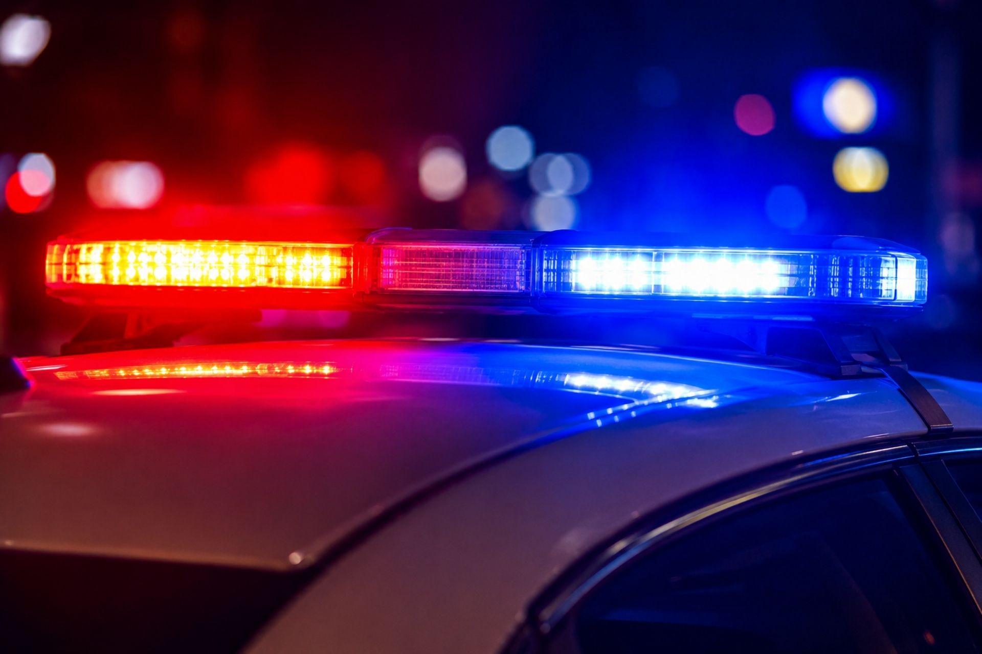 Flashing red and blue police lights on top of a cruiser at night.