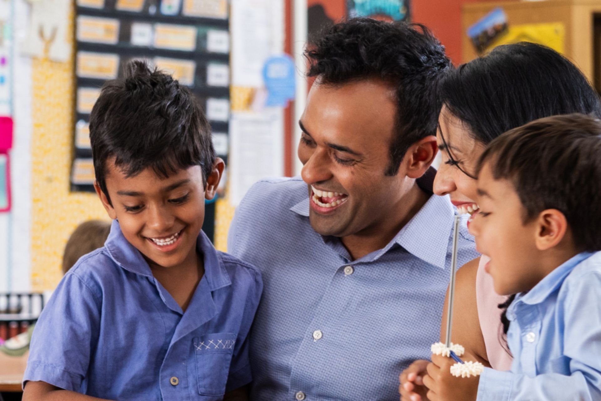 Vivek Ramaswamy smiling and interacting with children in a classroom setting.