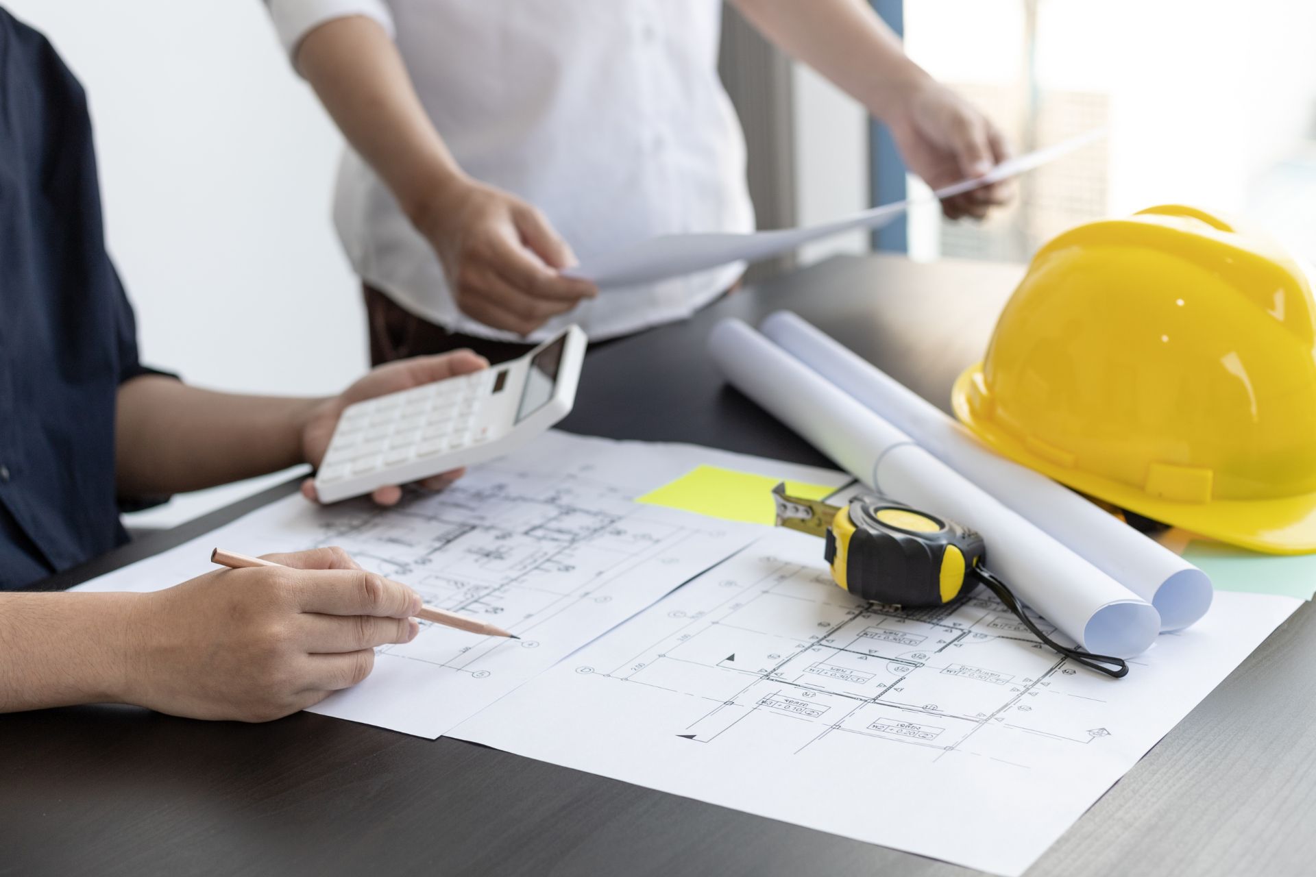 Architectural team reviewing building blueprints with a yellow hard hat for Westline Flats apartments in Cincinnati.