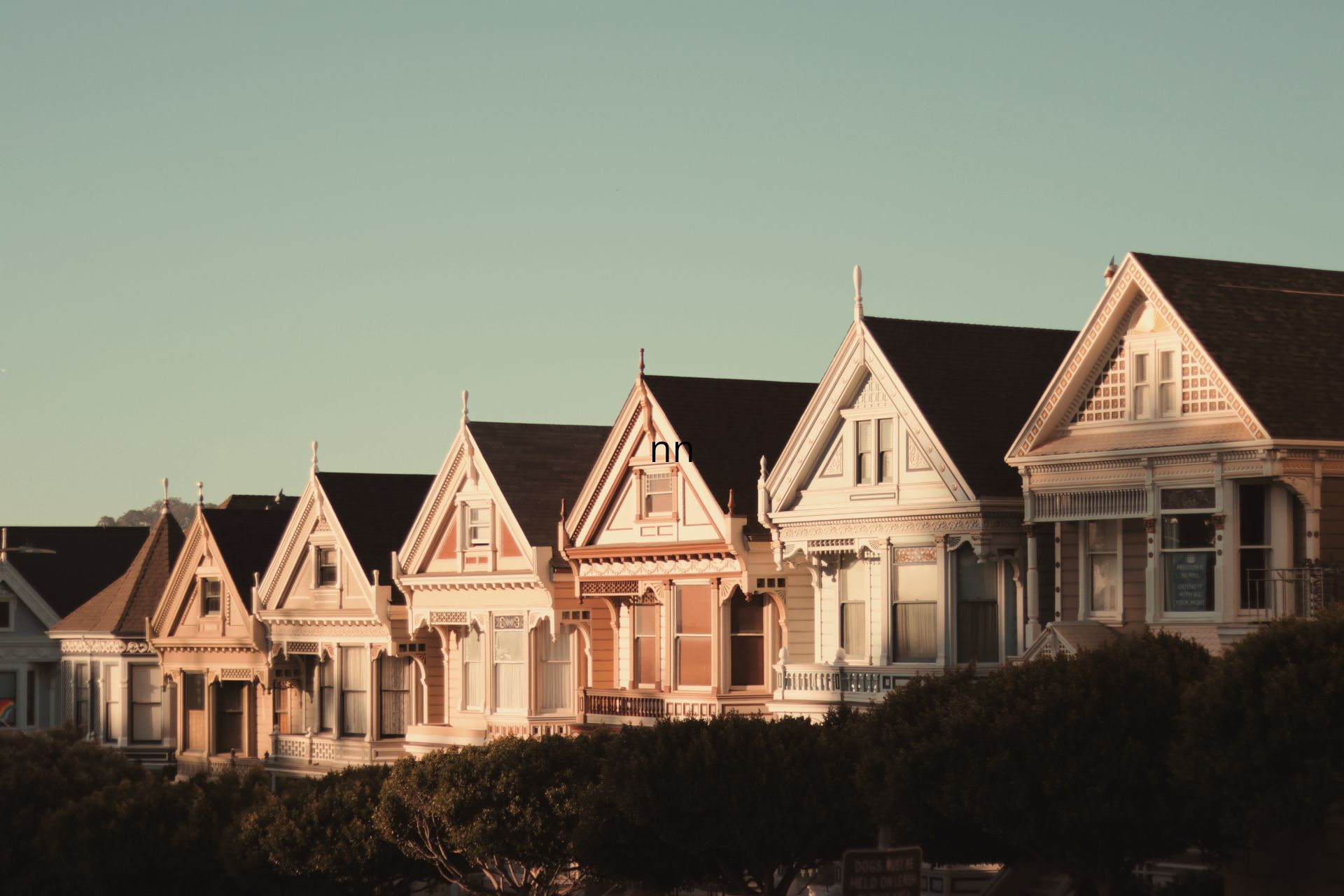 Row of Victorian-style houses with pointed gables in warm evening light