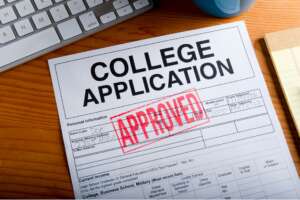 A printed college application form resting on a desk with a large red "APPROVED" stamp across it.