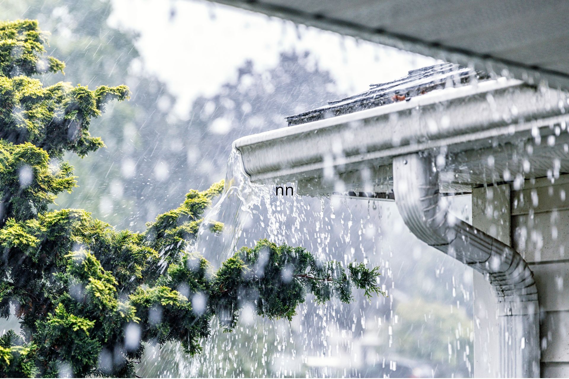 Heavy rain pouring off a roof and gutter during a downpour.