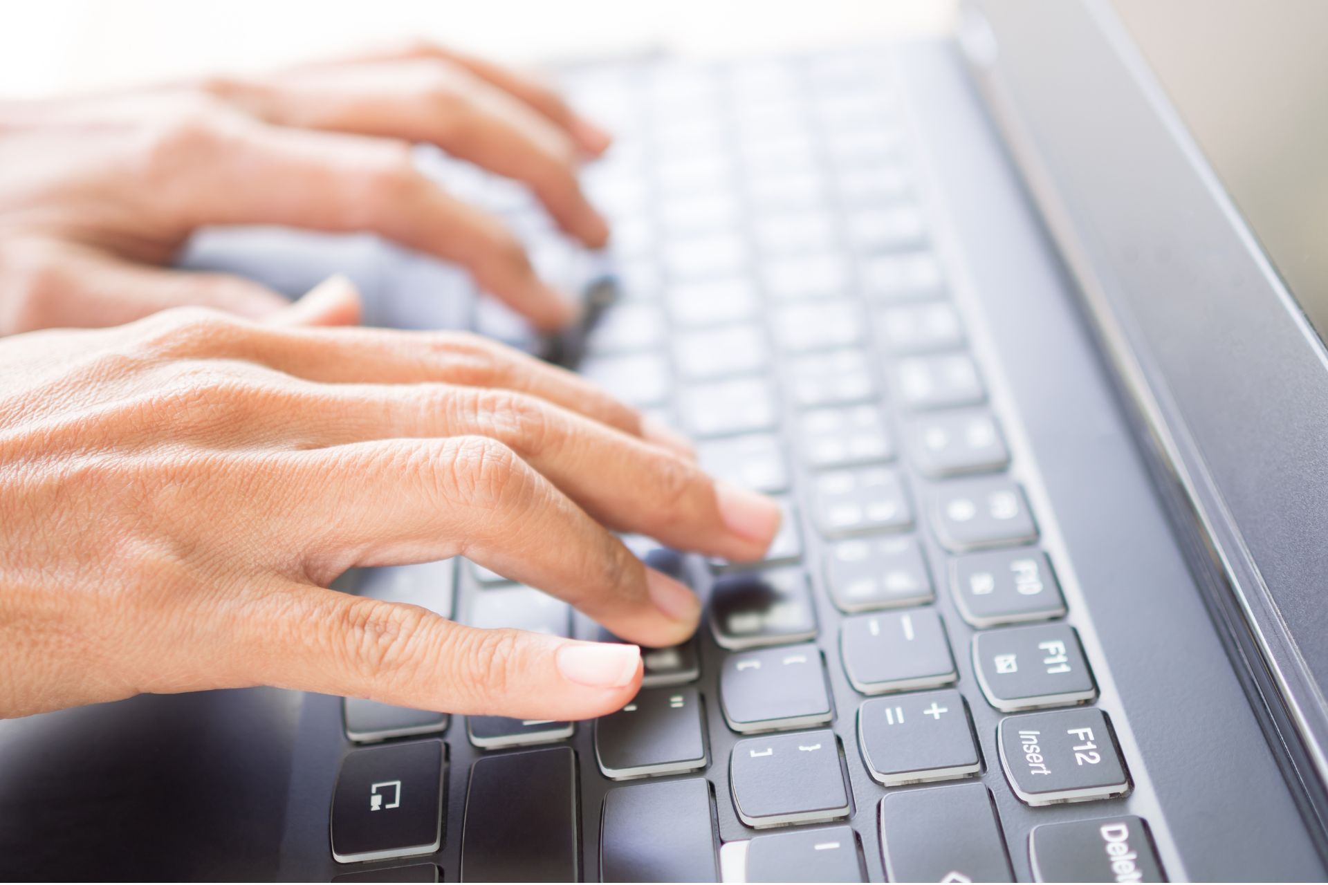 Close-up of hands typing on a laptop keyboard