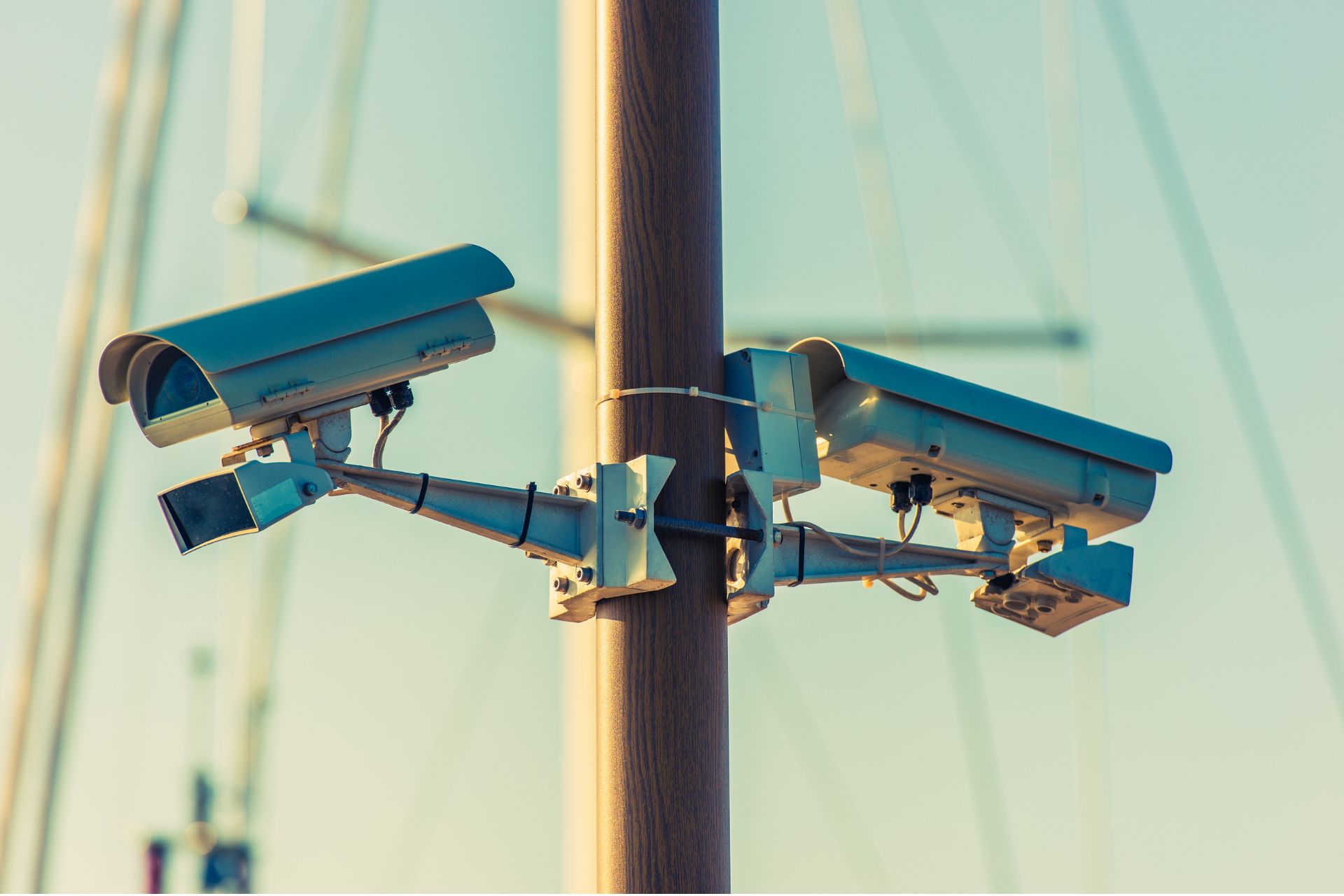 Two security cameras mounted on a utility pole, pointing in opposite directions.