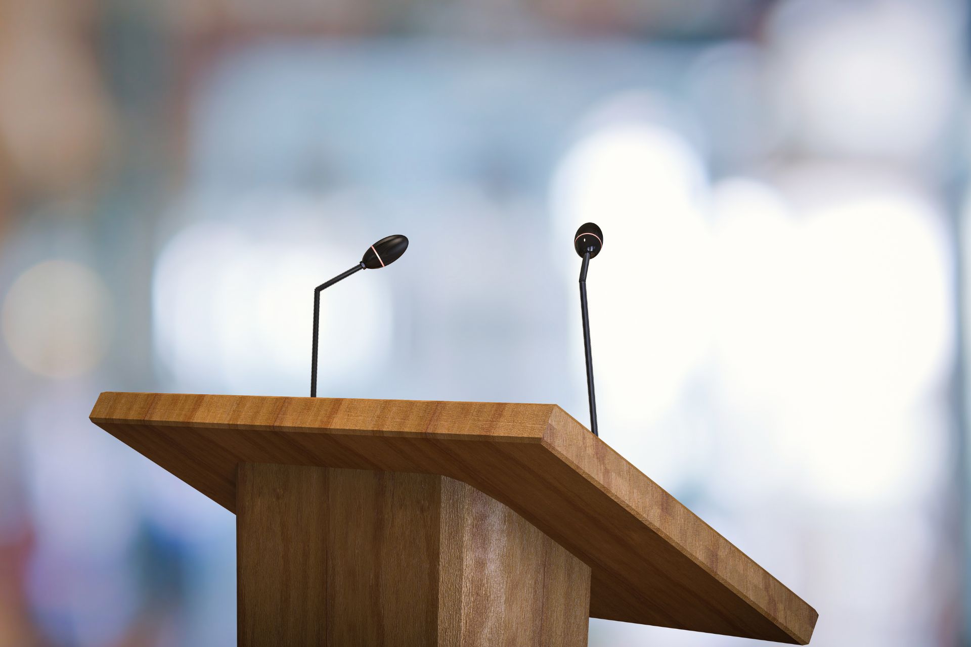 Wooden podium with two microphones in front of a blurred background