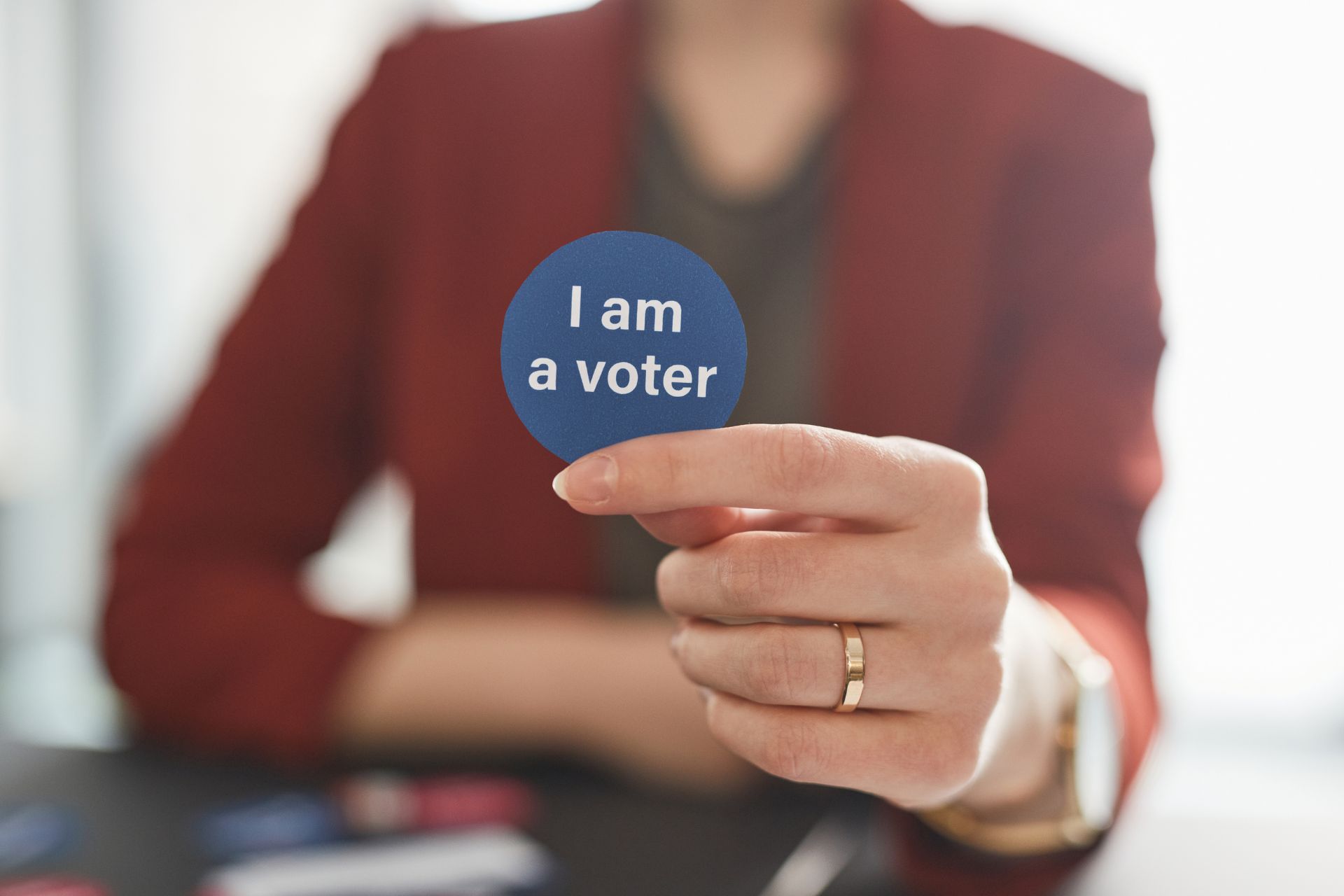 A person holding a blue "I am a voter" sticker.